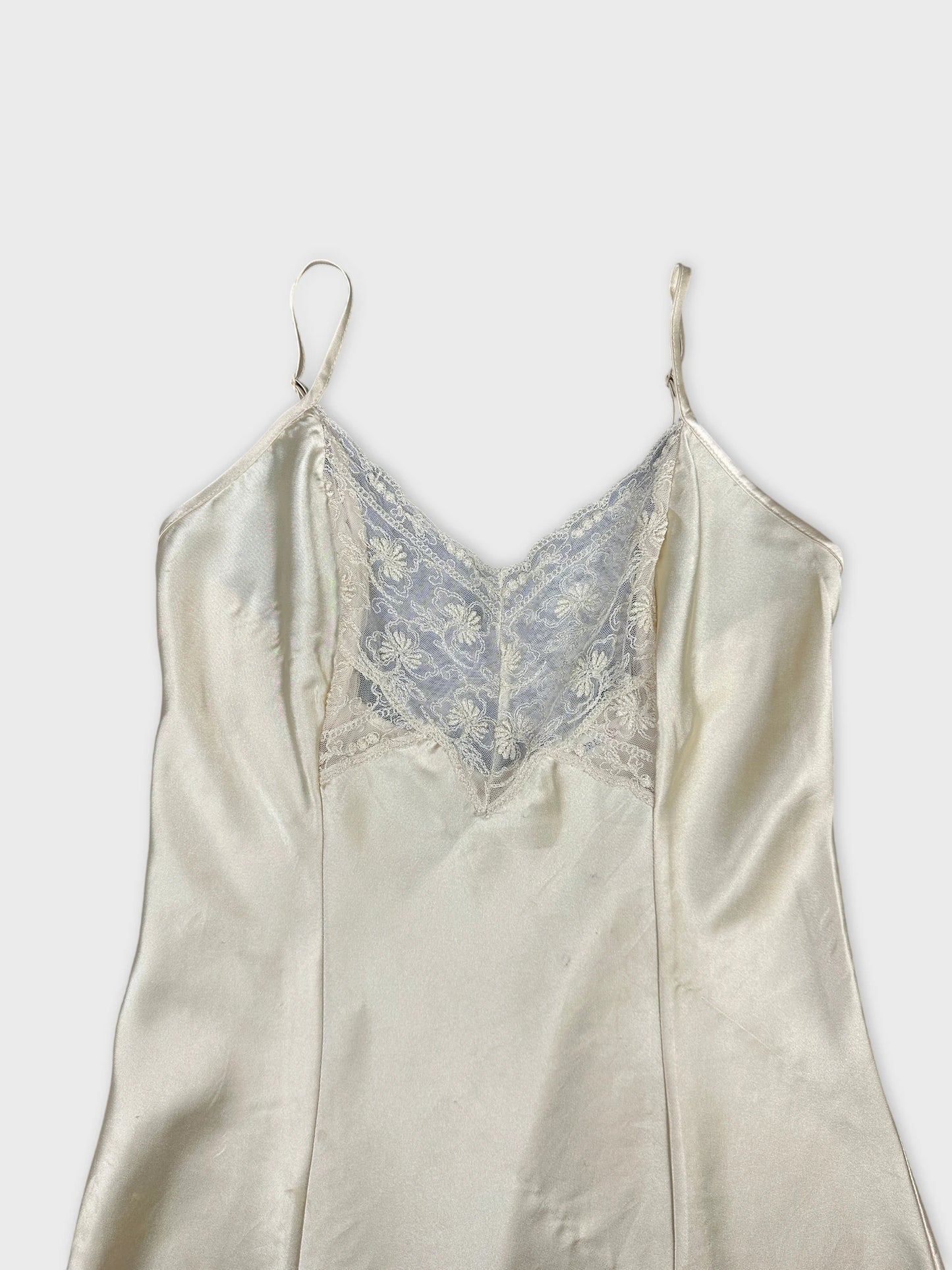 Detail view of a vintage women's silk top in cream with lace trim.