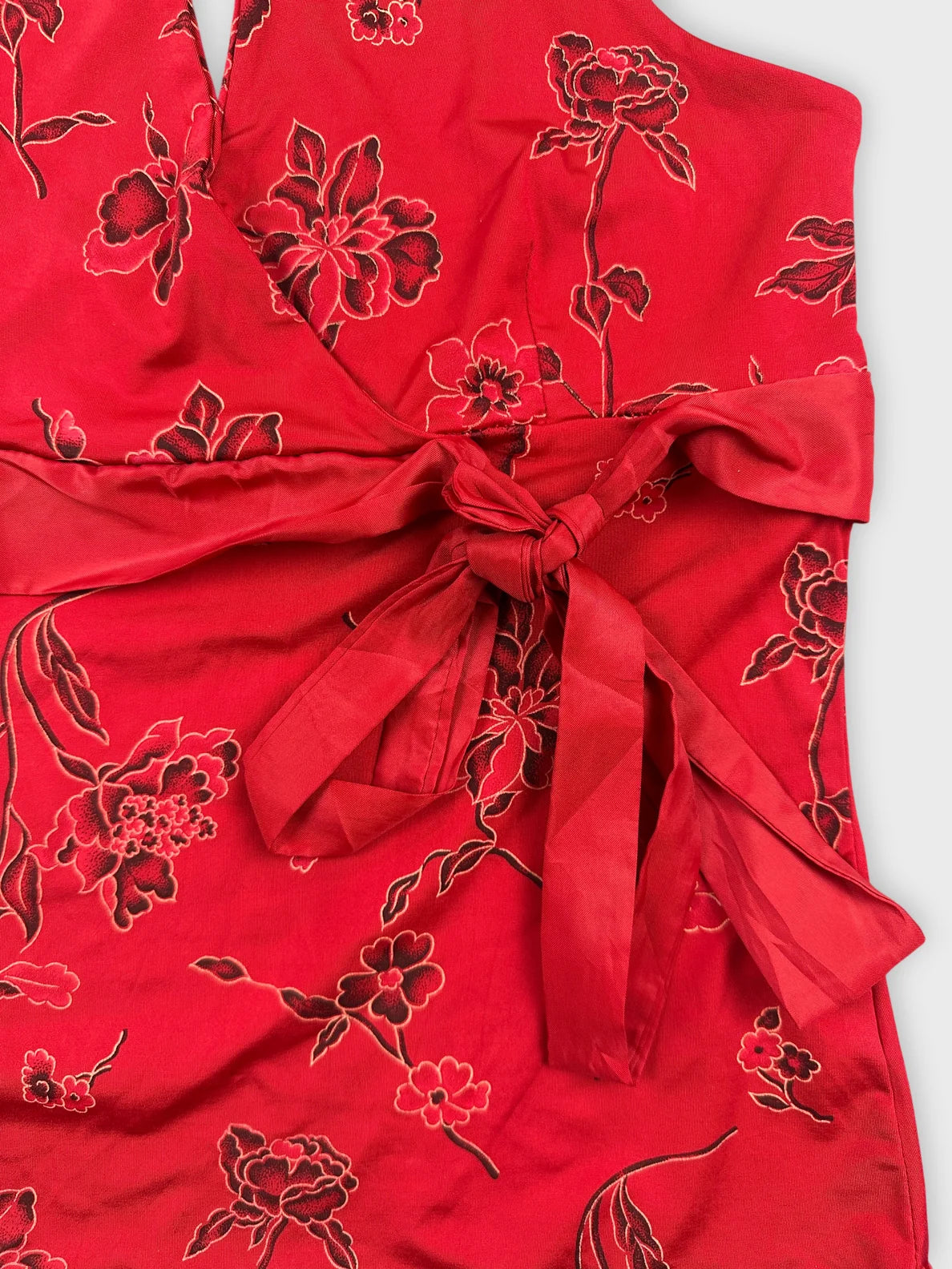 Detail view of a red floral vintage top with a tie belt.