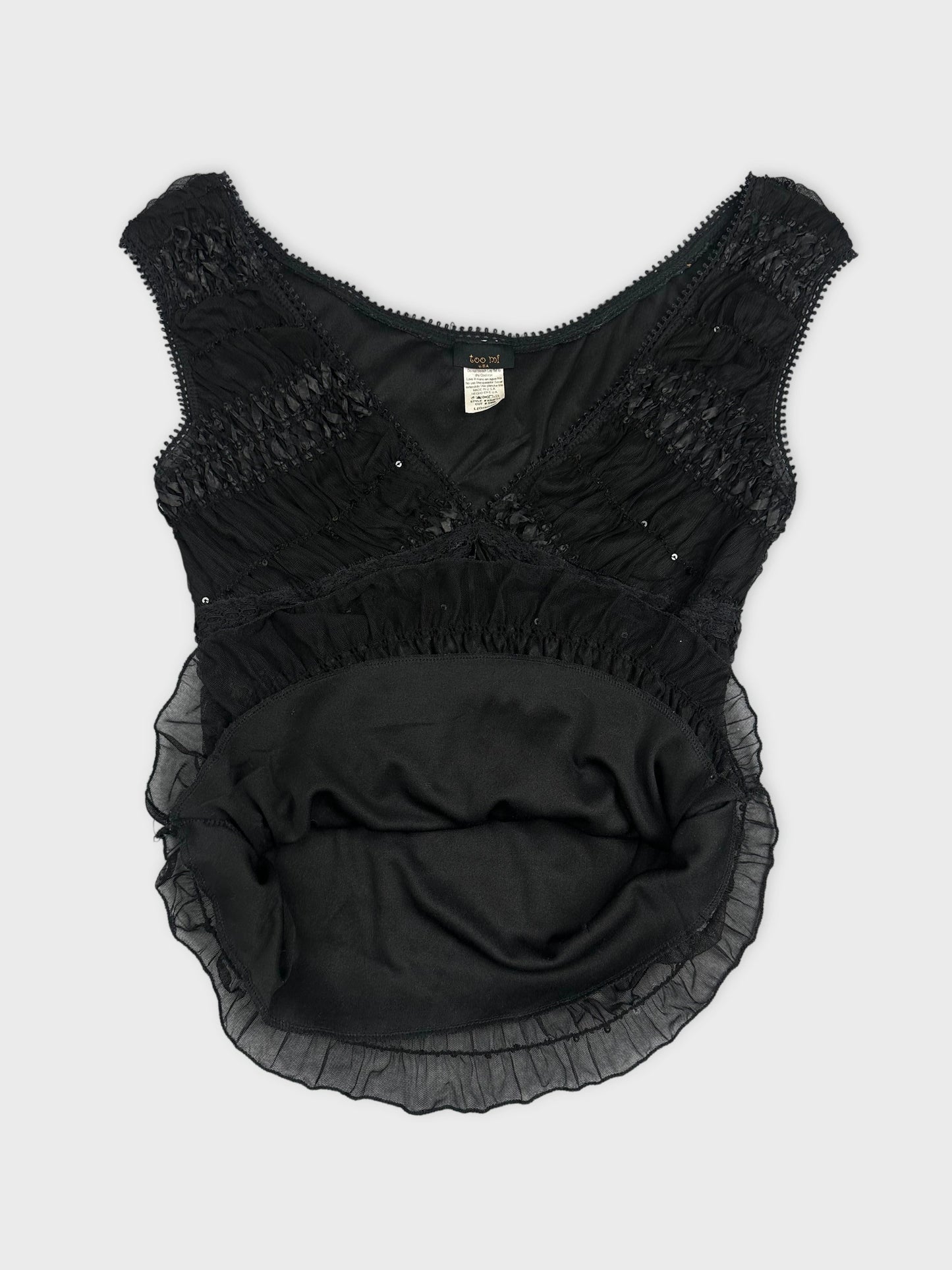 Detail view of a black vintage upper body top with ruffled trim.