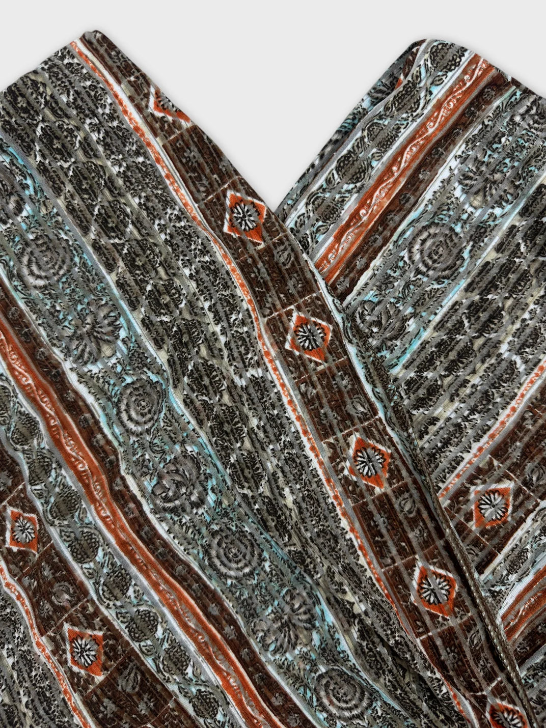Detail view of a vintage top in gray with floral and geometric patterns.