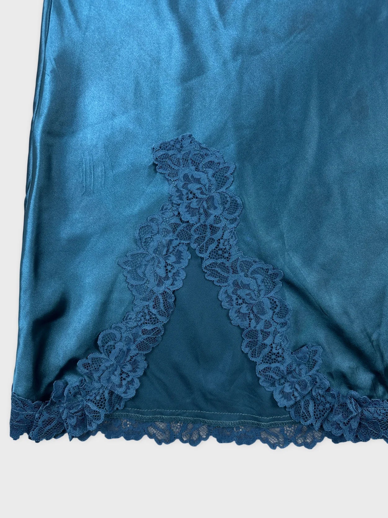 Detail view of a teal upper body top featuring lace trim.