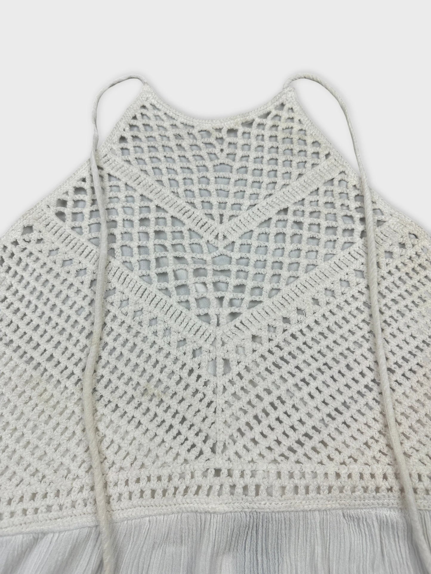 Detail view of a white crochet top featuring intricate geometric patterns.