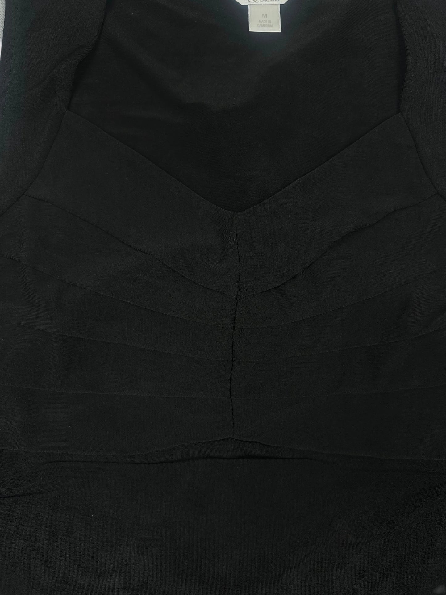 Detail view of a black upper body top with pleated design.