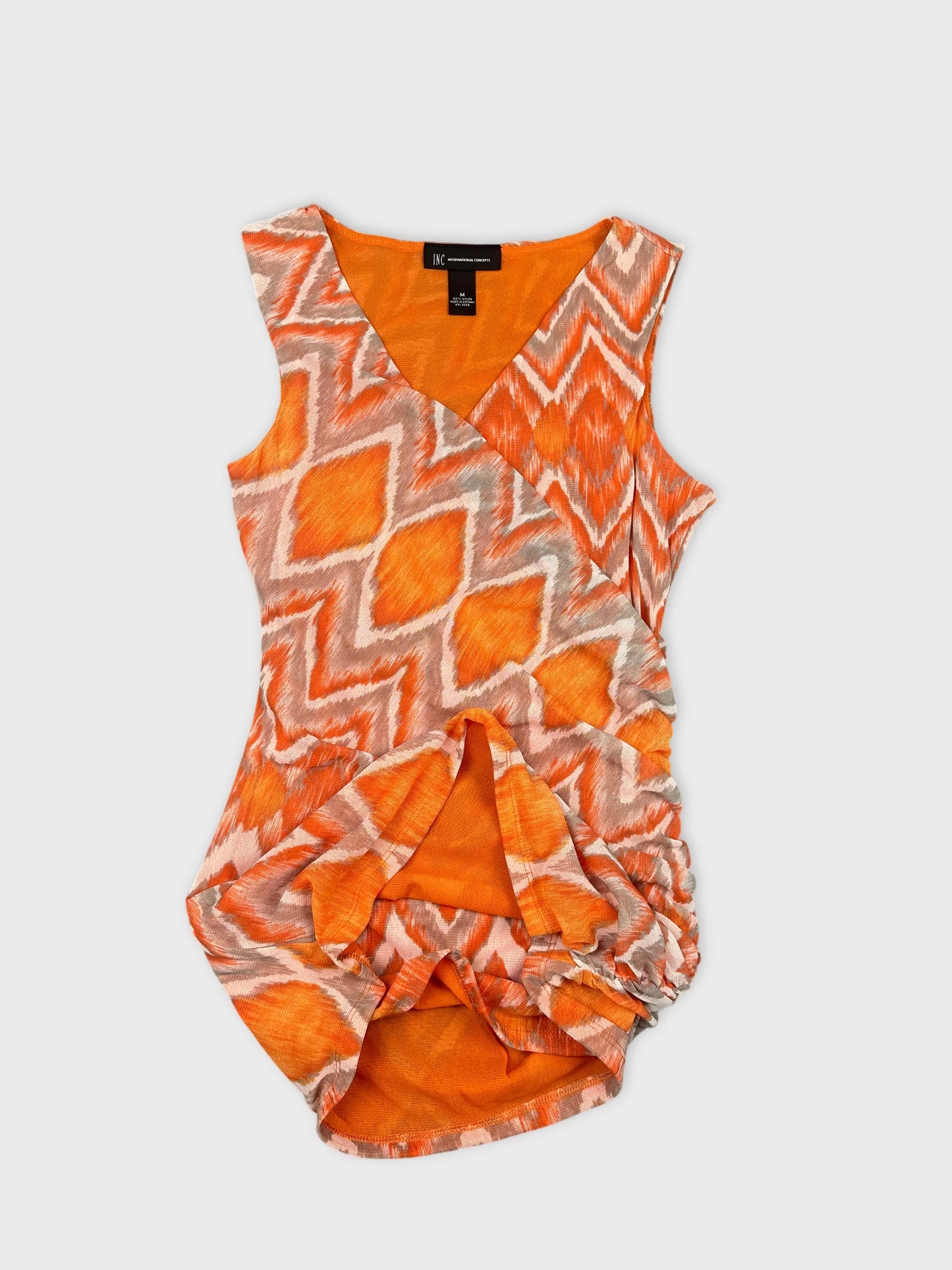 Detail view of a women's orange top featuring a zigzag pattern.