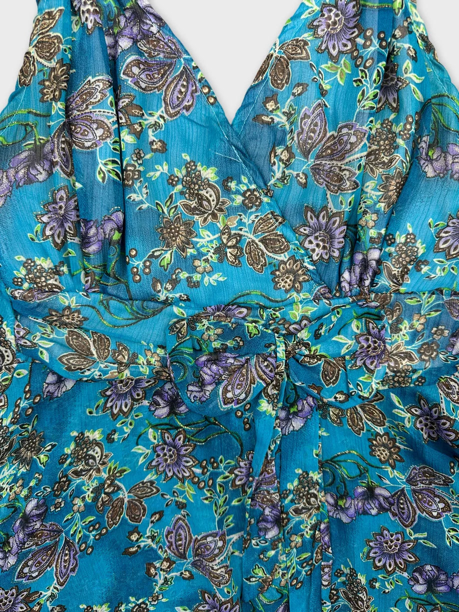 Detail view of a turquoise floral women's top with a bow detail.