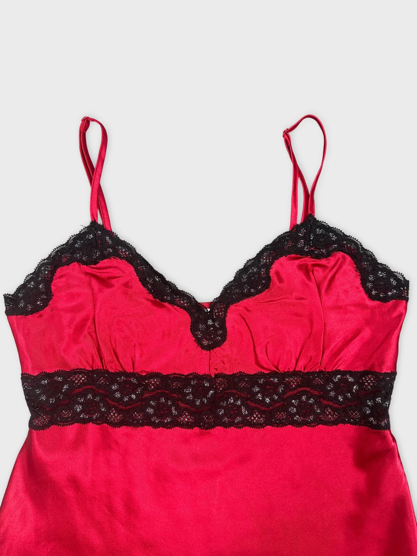 Detail view of a red satin top with black lace trim.
