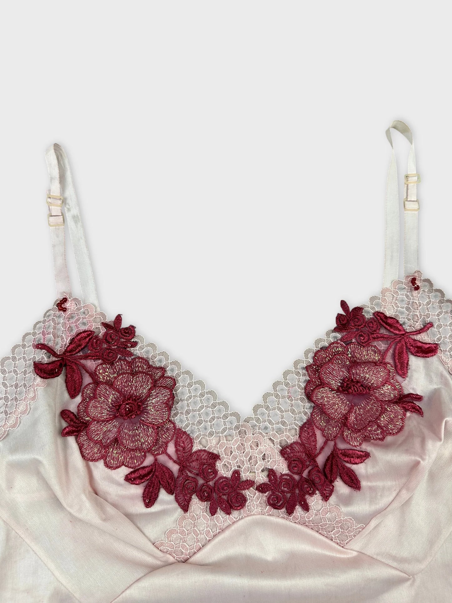 Detail view of a pink women's top with burgundy floral embroidery.