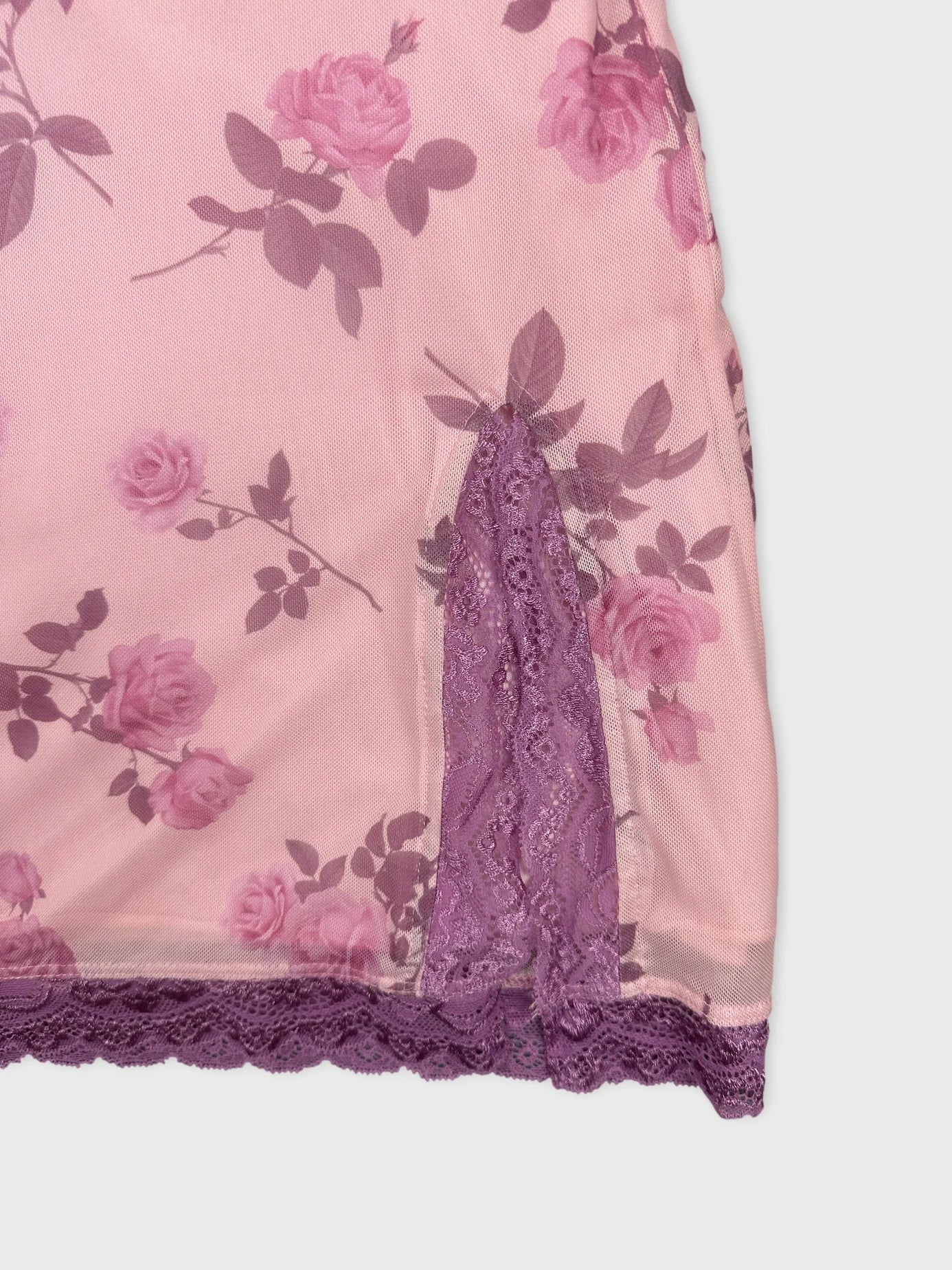Detail view of pink floral upper body top with purple lace trim.