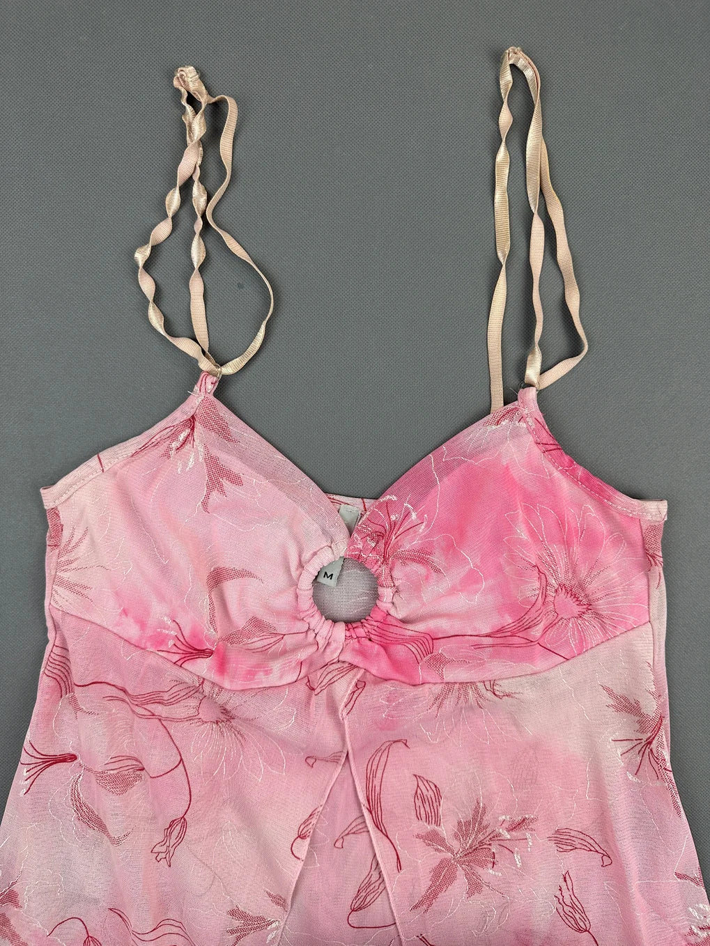 Detail view of a pink vintage upper body top with floral pattern and spaghetti straps.