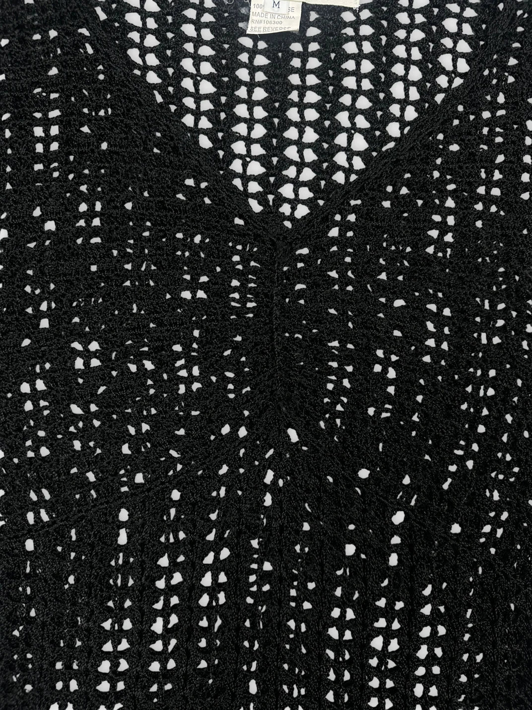 Detail view of a black crochet top with a v-neck design.