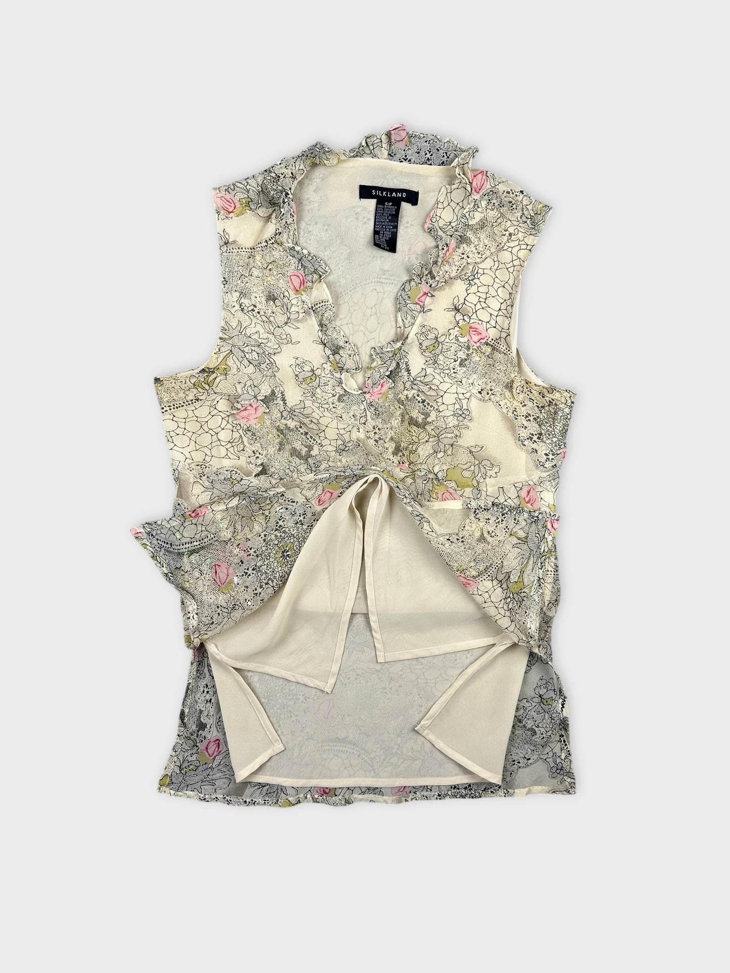 Detail view of floral vintage top in cream with ruffled neckline.