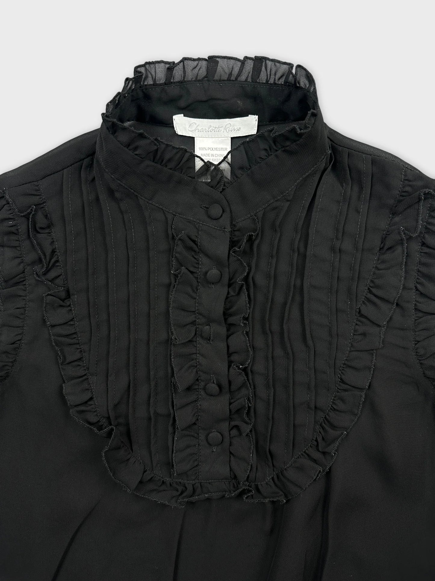 Detail view of a black vintage top featuring ruffled trim and button front.