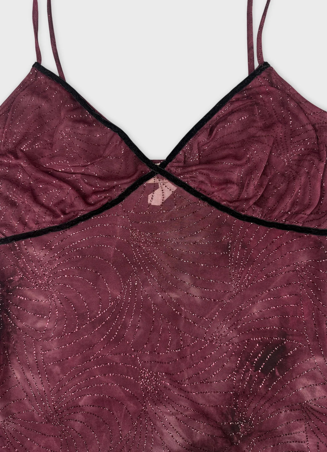 Detail view of a burgundy upper body top with swirling patterns.