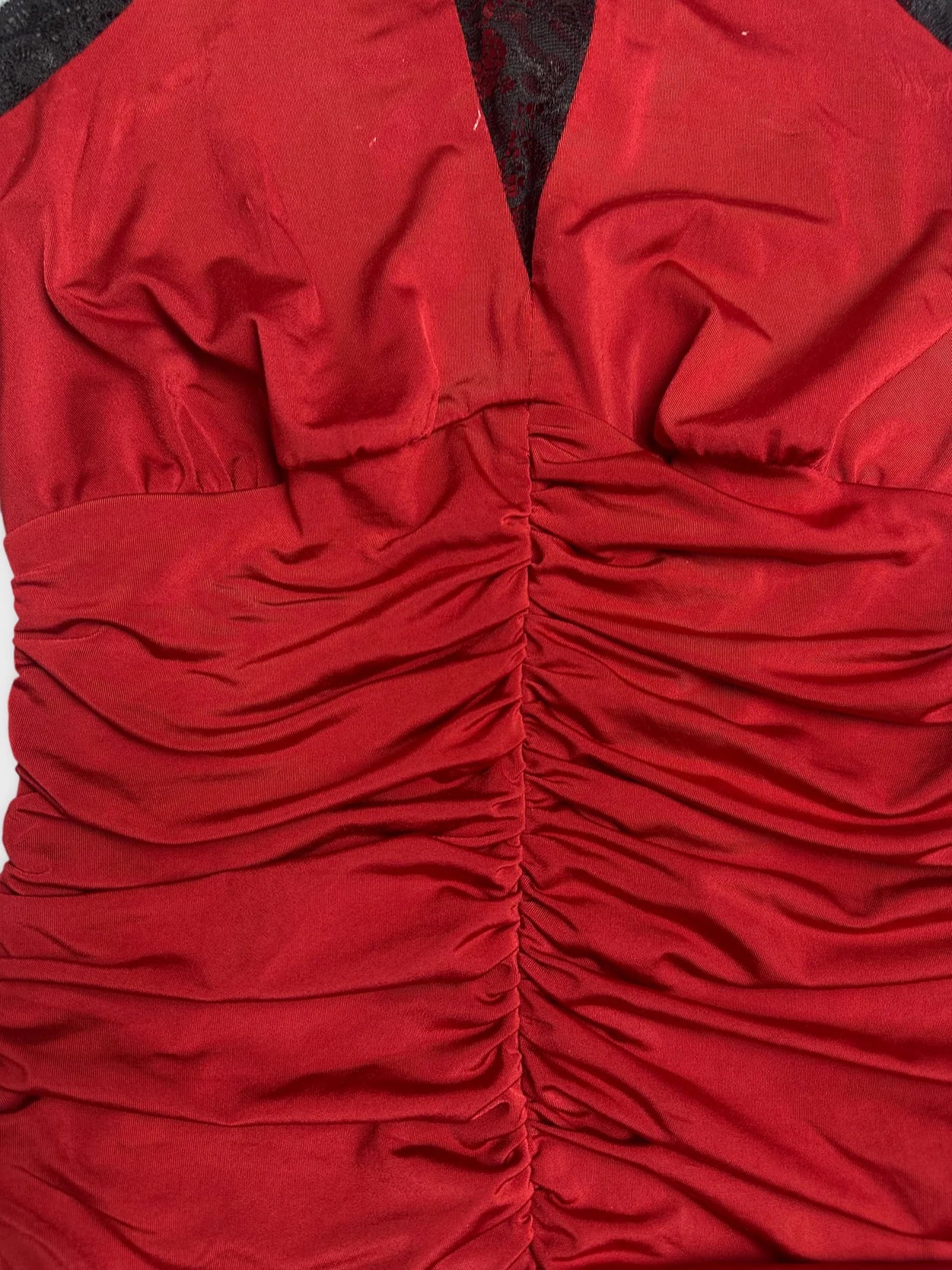 Detail view of a red vintage top featuring gathered fabric and lace trim.