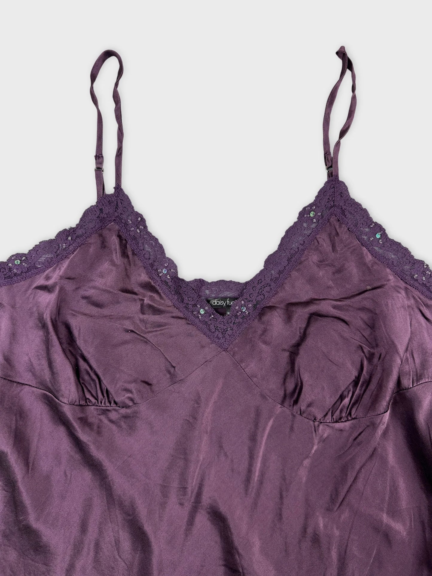 Detail view of a purple satin camisole with lace trim.