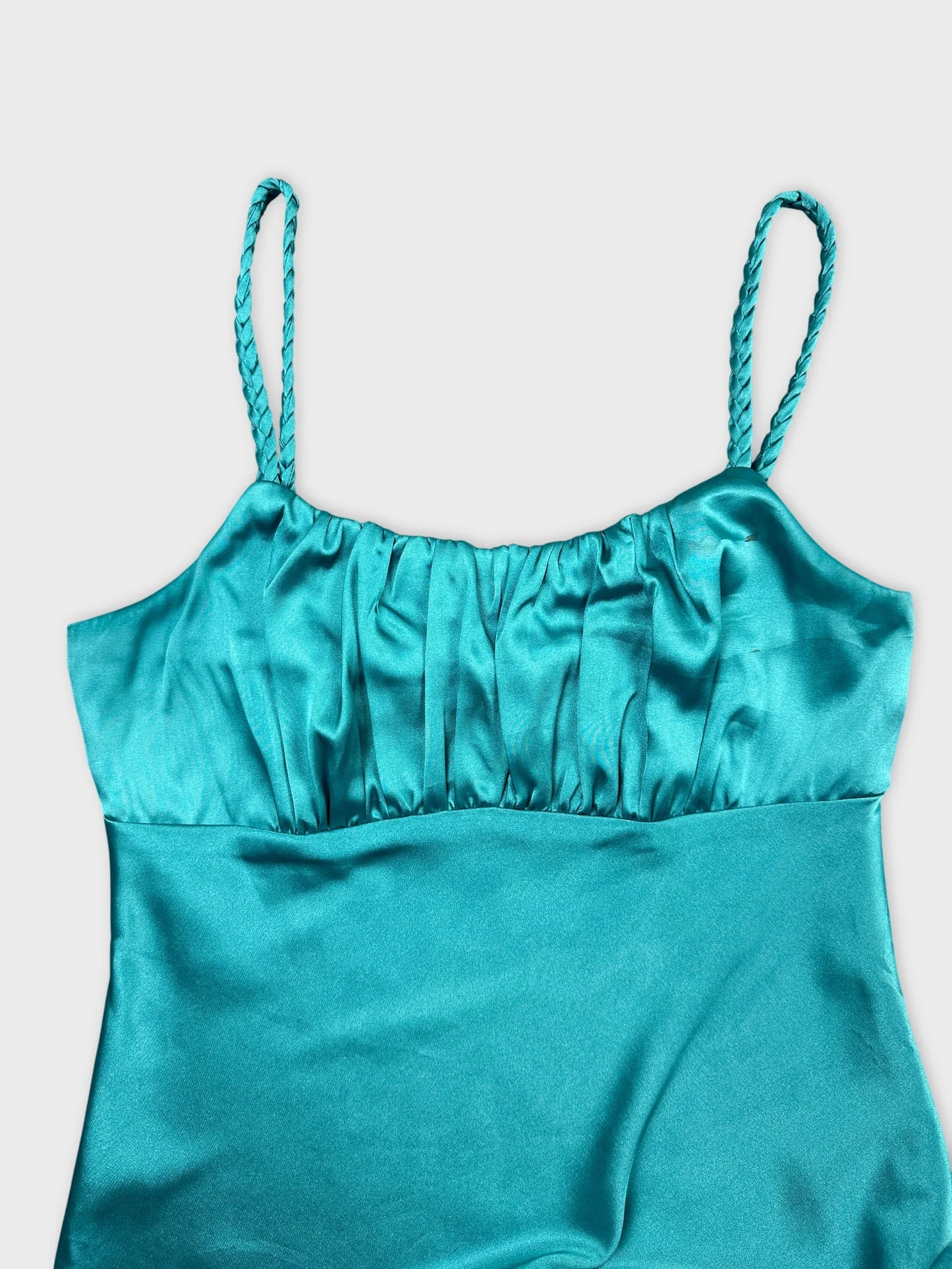 Detail view of a teal upper body top with gathered fabric and braided straps.