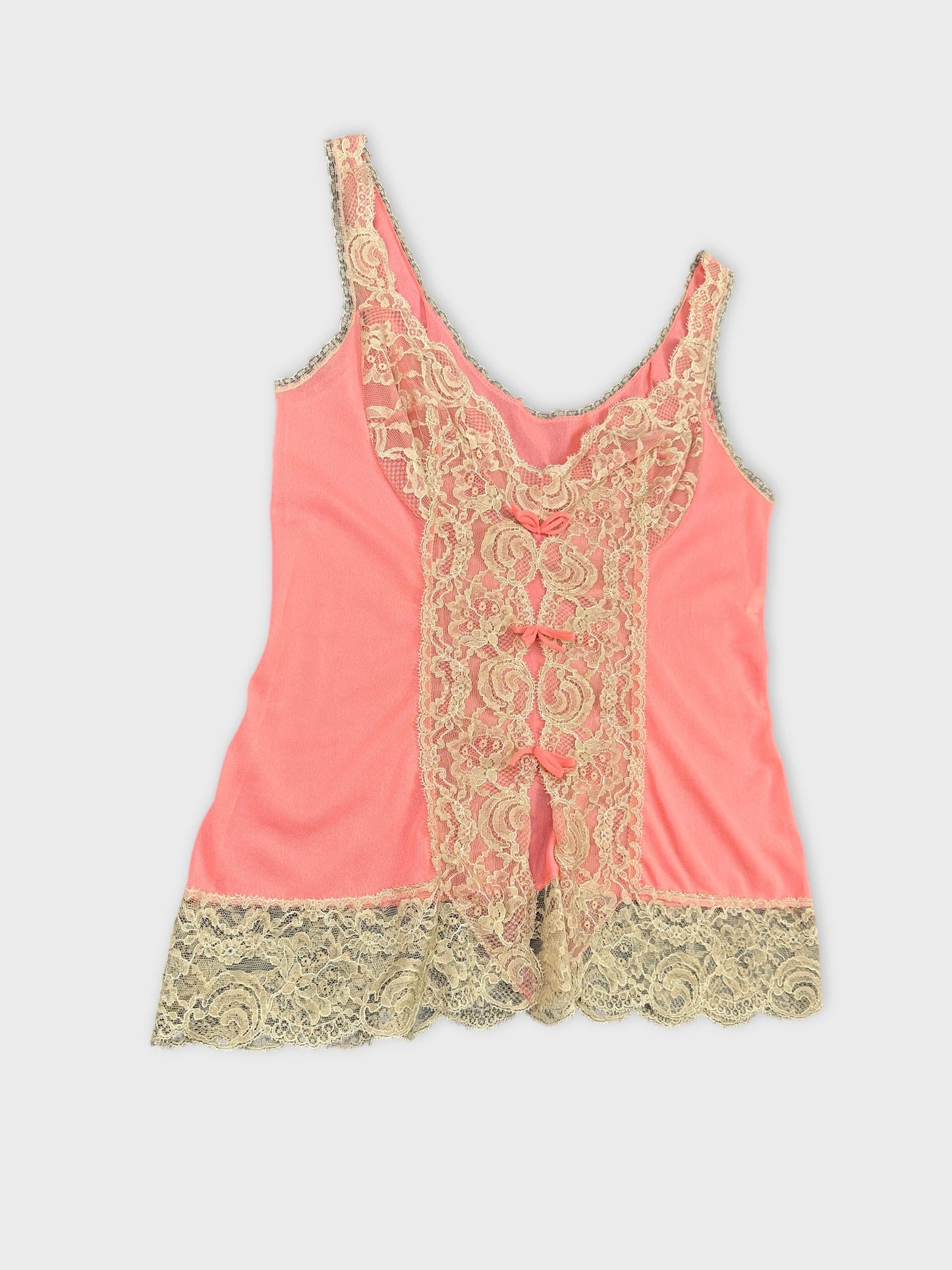 Detail view of a coral vintage top with lace trim and embellishments.