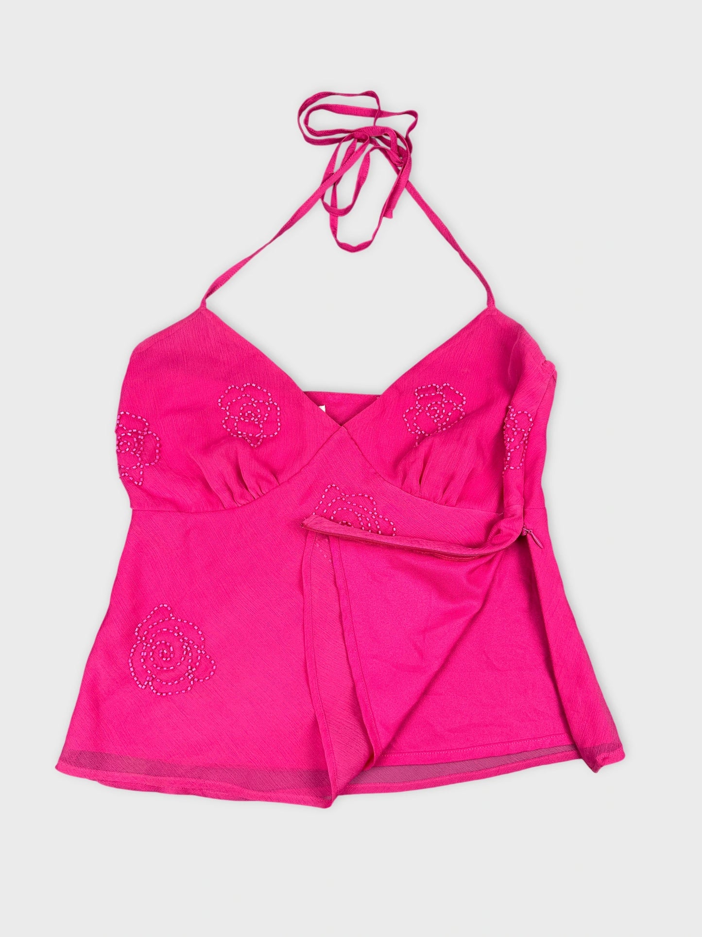 Detail view of a pink halter top featuring floral embellishments.