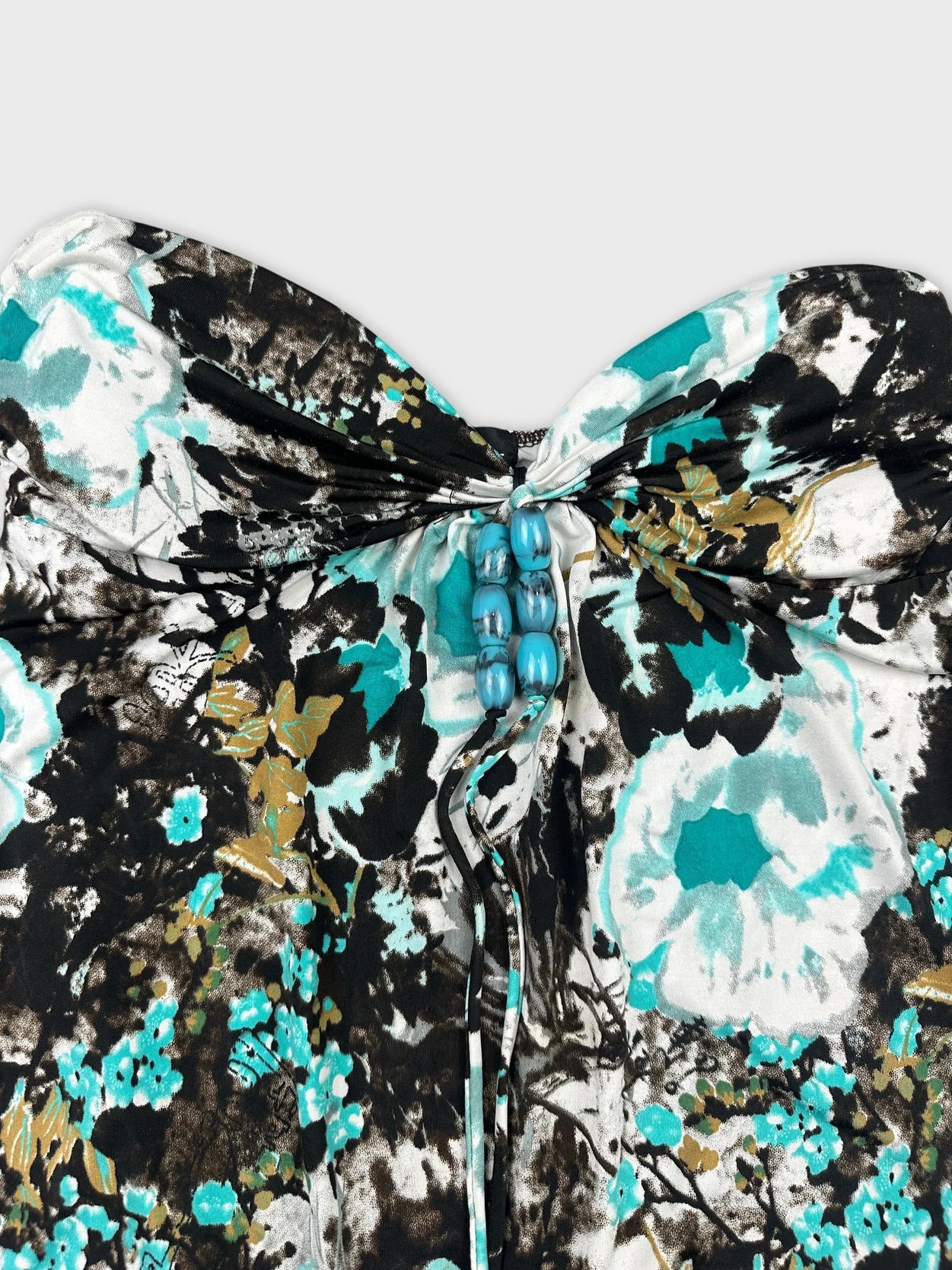 Detail view of a vintage women's top in black and teal floral pattern.