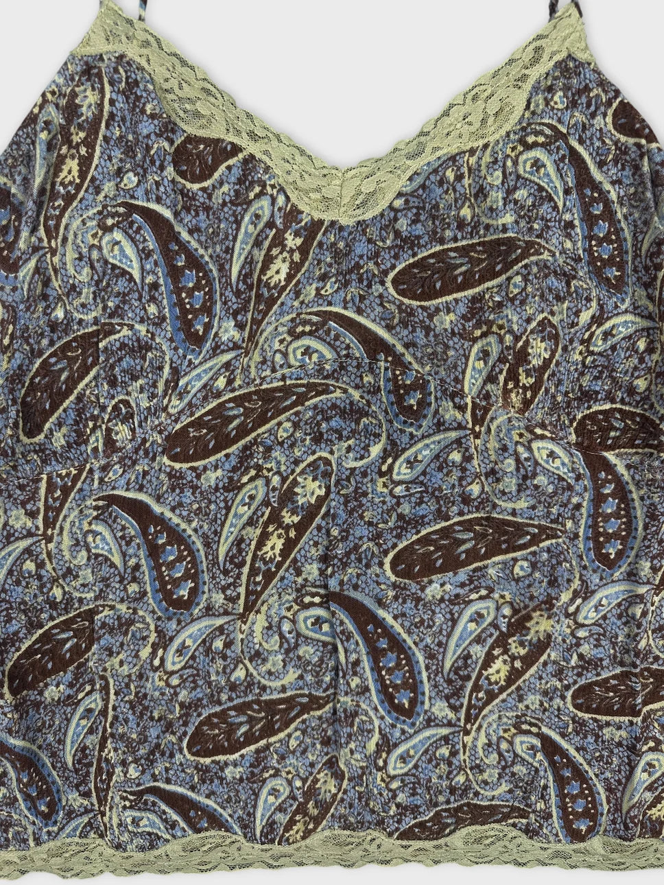 Detail view of a brown and blue paisley print camisole with lace trim.