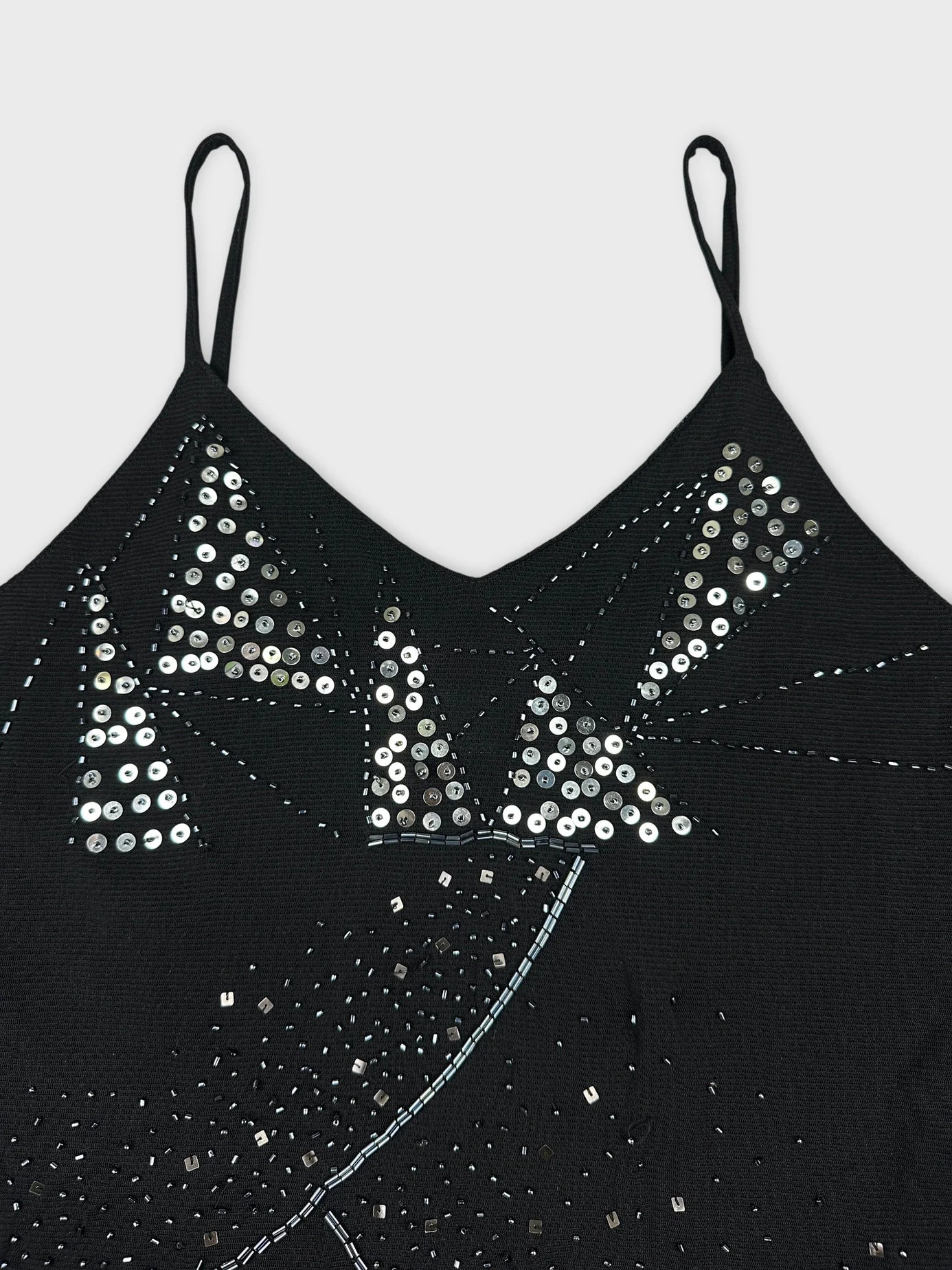 Detail view of a black sleeveless top with sequin pattern.