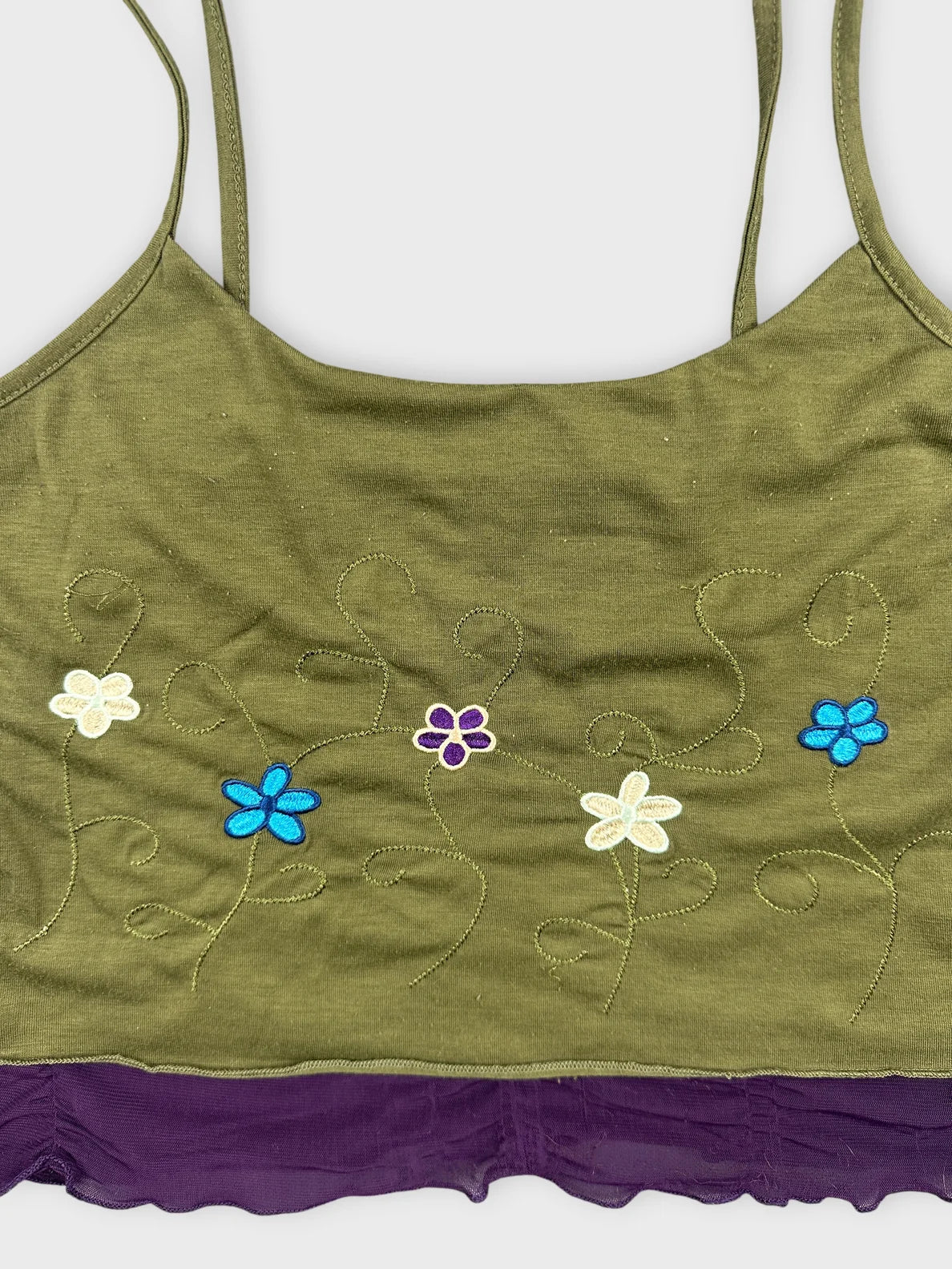 Detail view of a green floral tank top with purple trim.