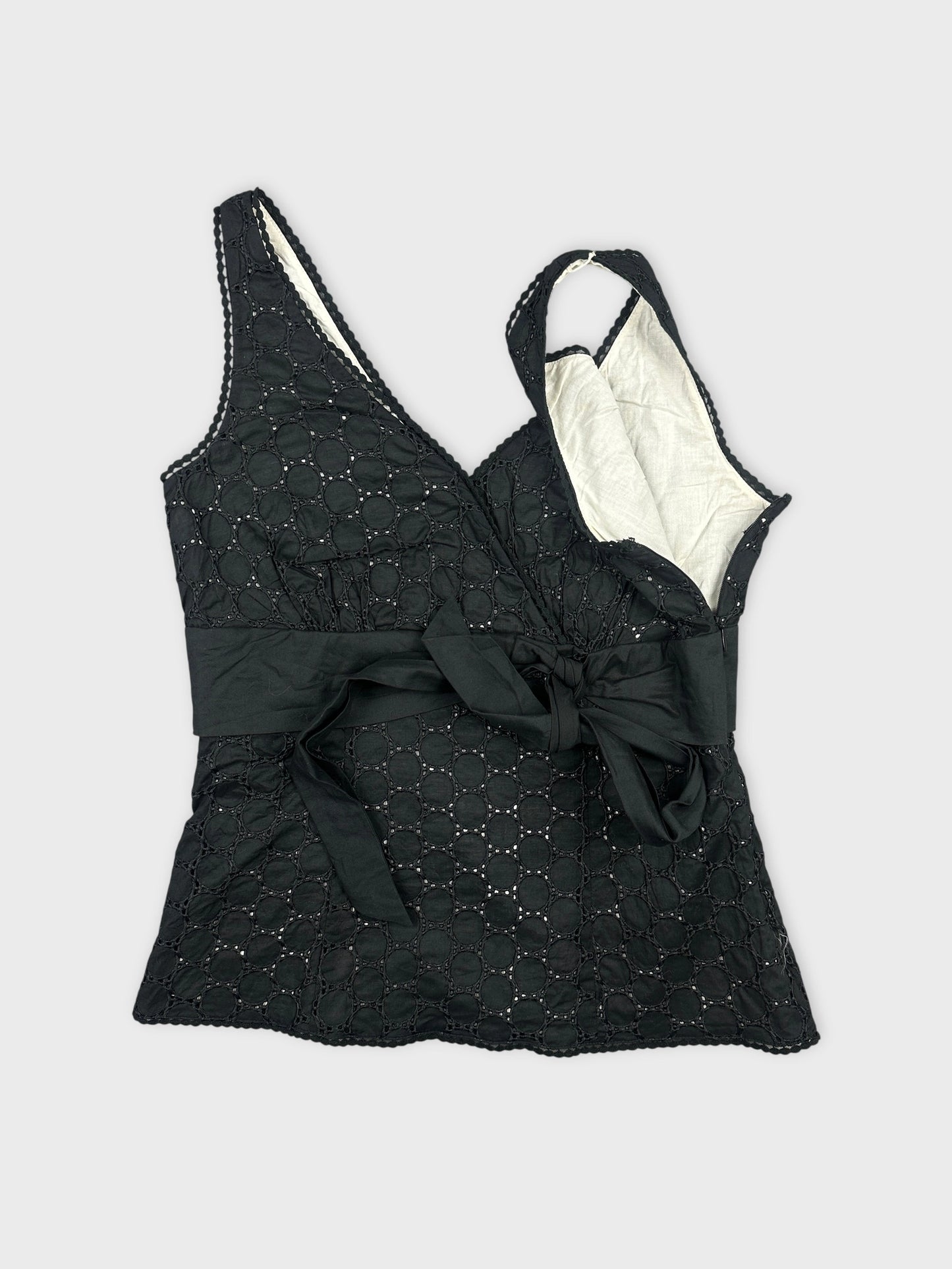 Detail view of a black vintage top with circular embroidery and tie waist.