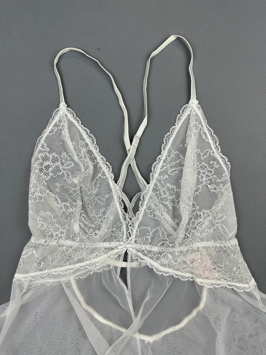 Detail view of a white lace bralette with silky straps.