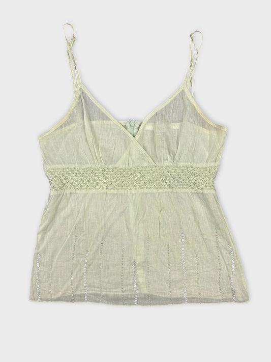Front view of a light green tank top with smocked waistband and beaded details.
