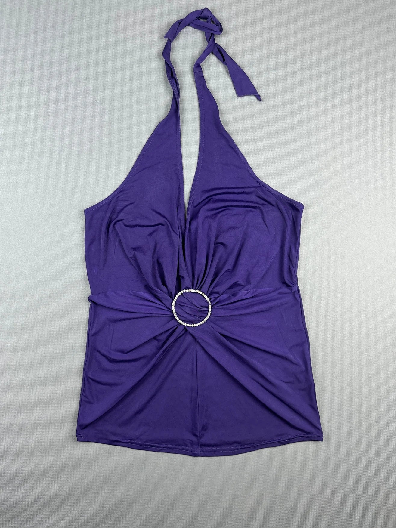 Purple halter top with twist detail and circular rhinestone accent front view.