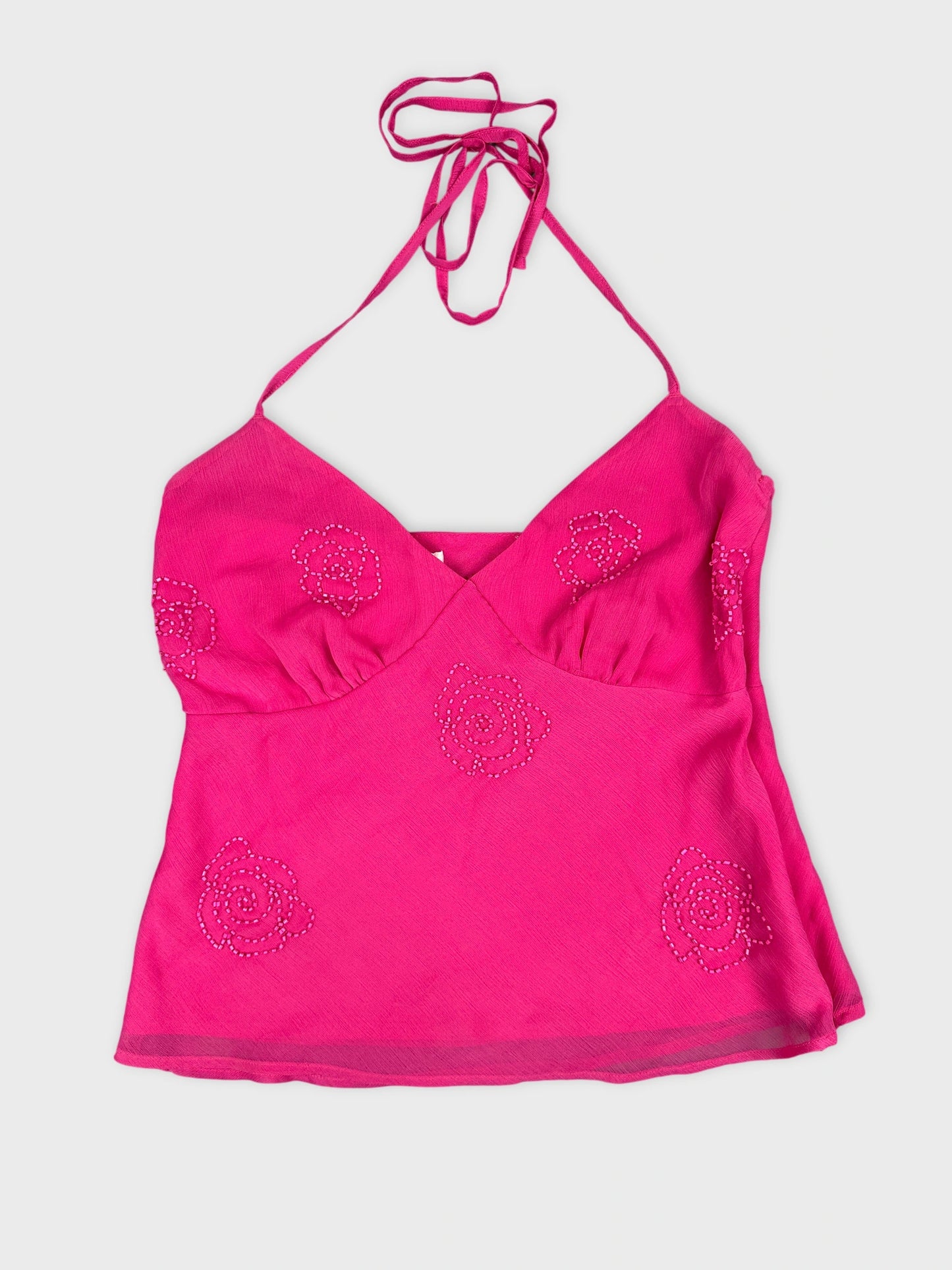 Front view of a pink halter-top with floral embellishments.