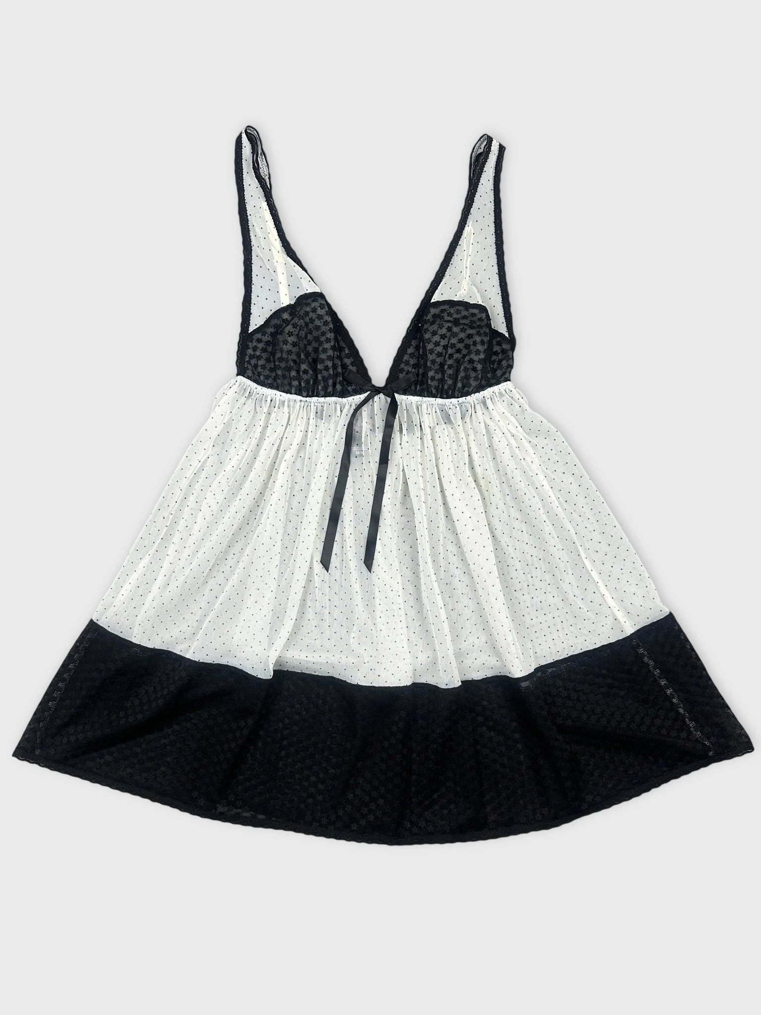 Front view of a black and white polka dot top with a tie detail.