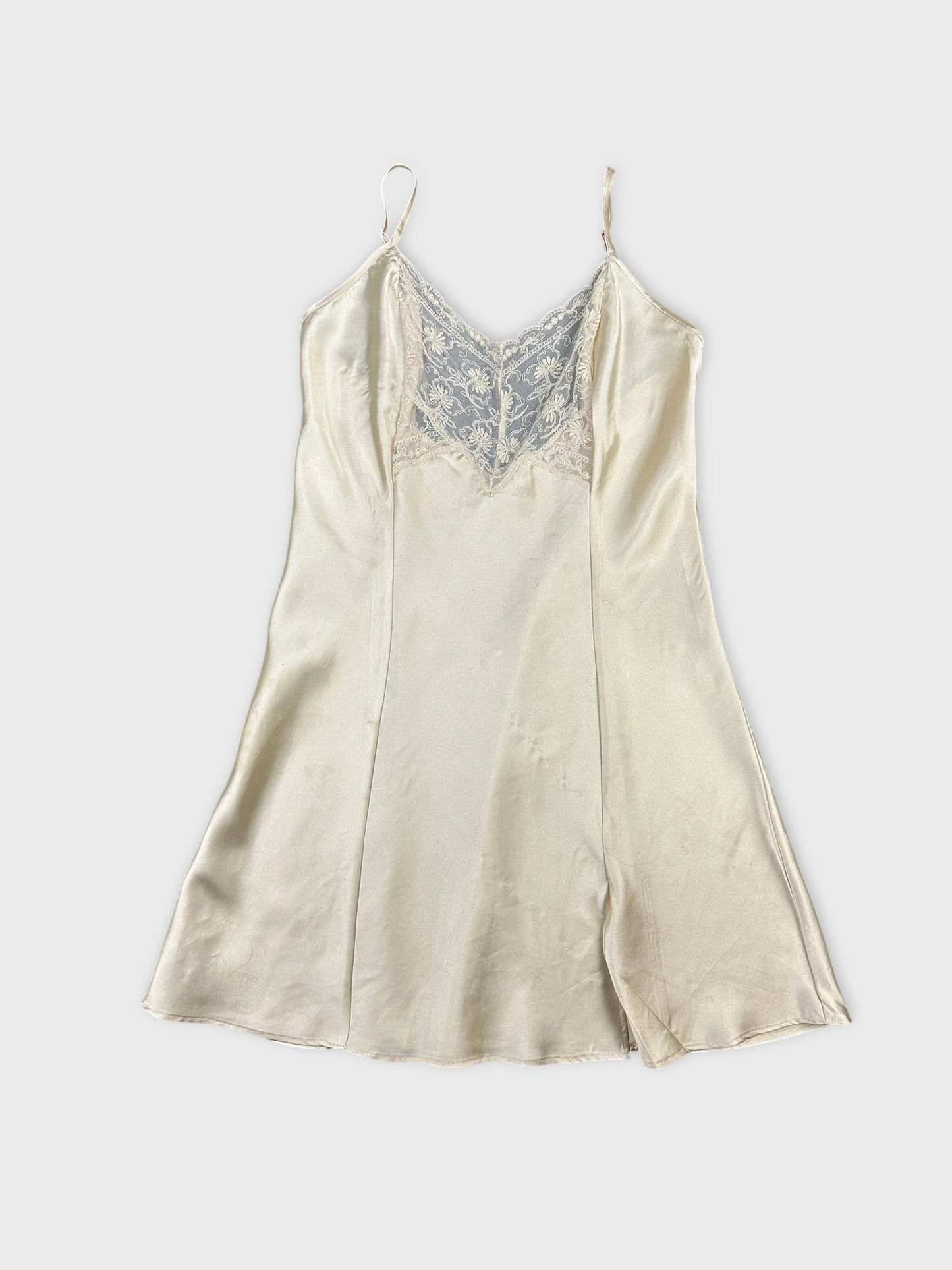Front view of a vintage cream camisole featuring delicate lace trim.