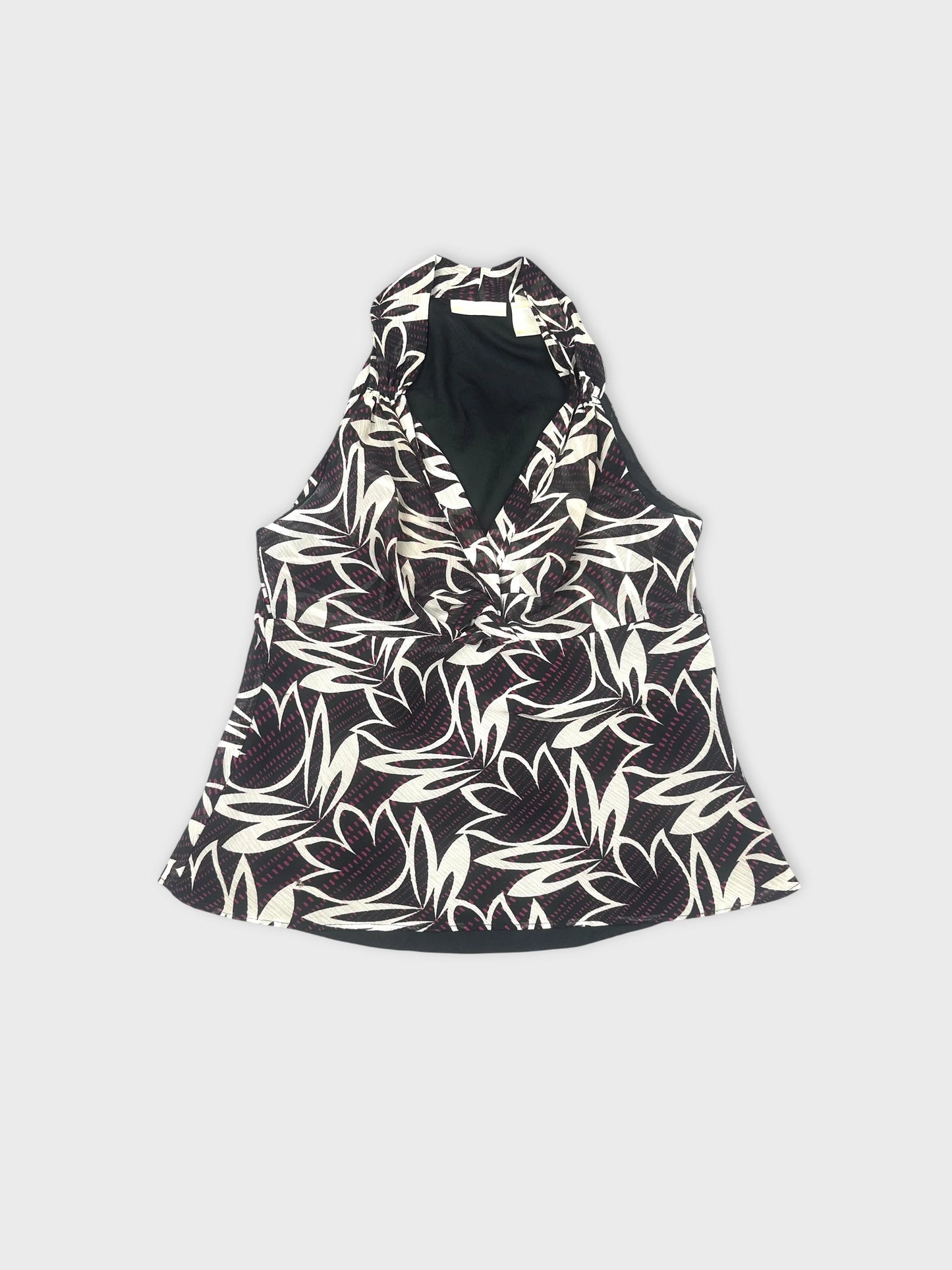 Front view of a black and white floral sleeveless top with a draped neckline.