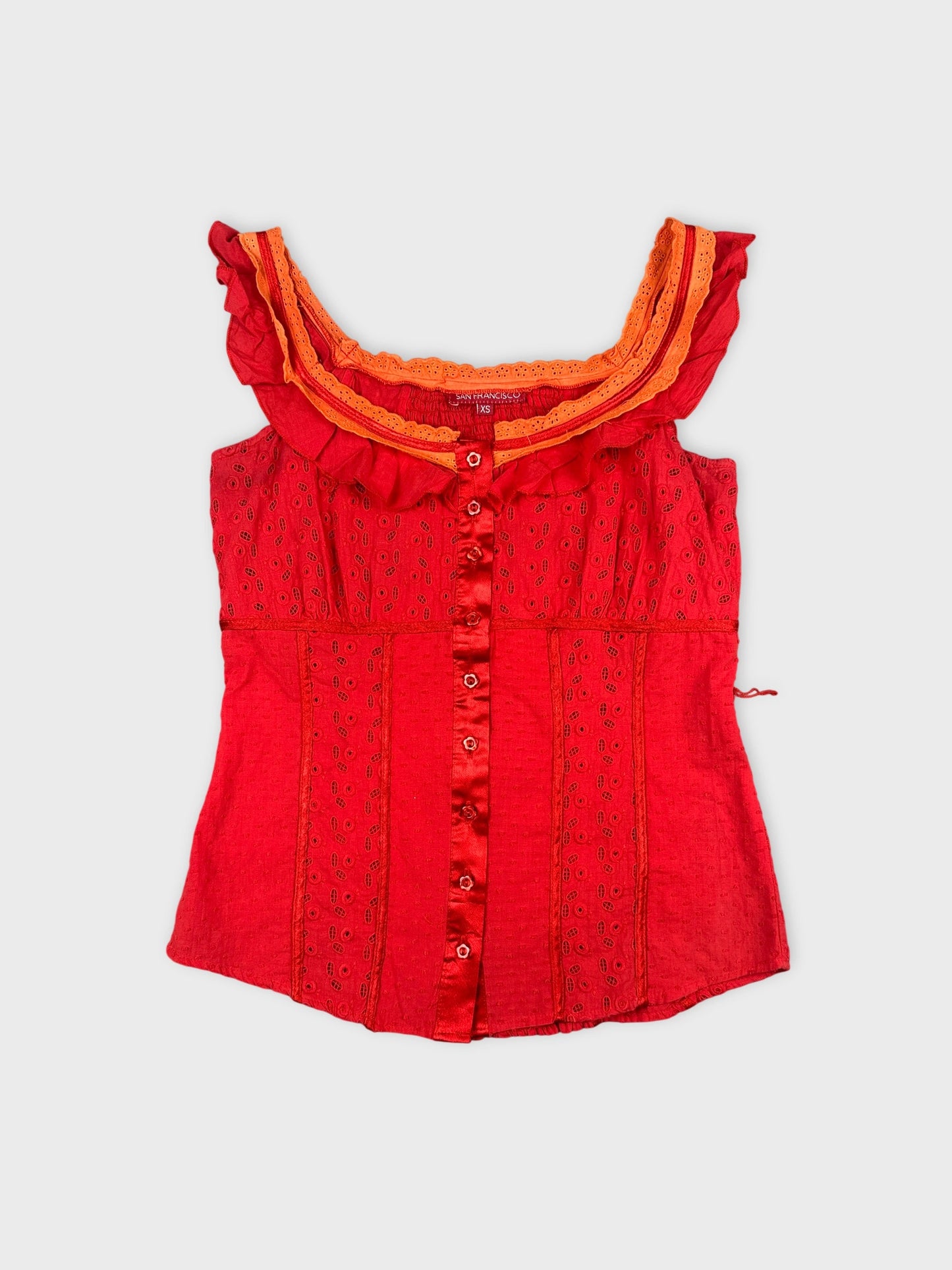 Front view of a red vintage top with ruffle trim and button detail.