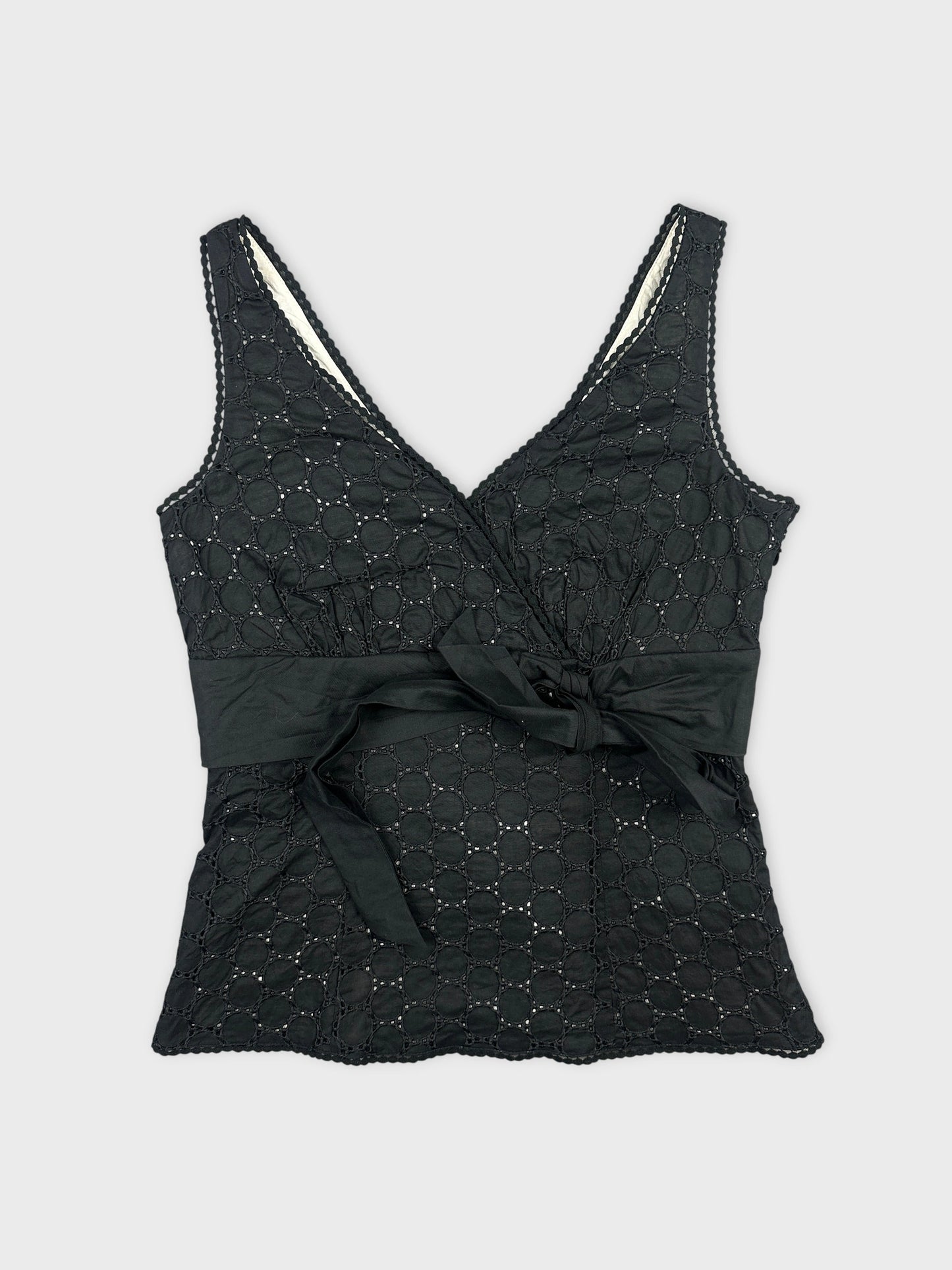Black wrap top with circular pattern and tie detail front view.