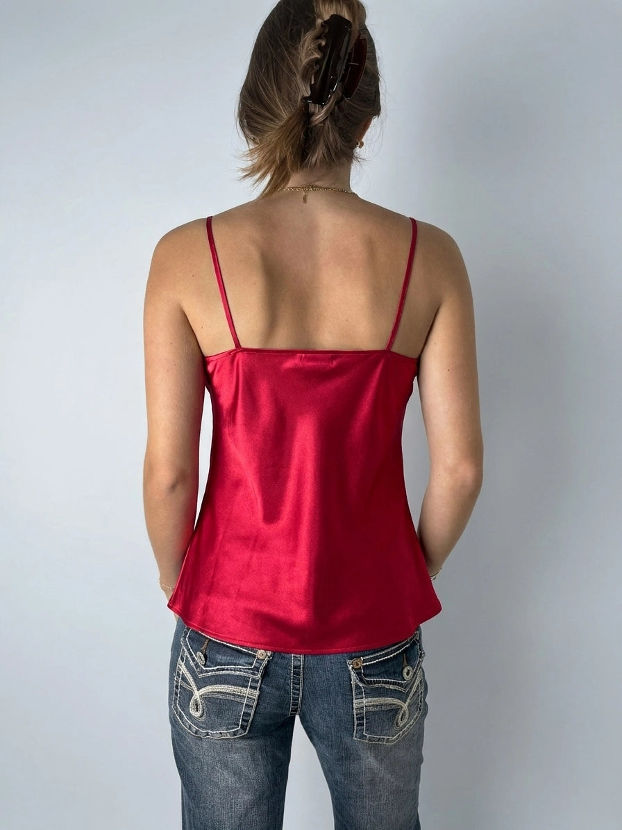 Back view of a red satin spaghetti strap top with flared shape.
