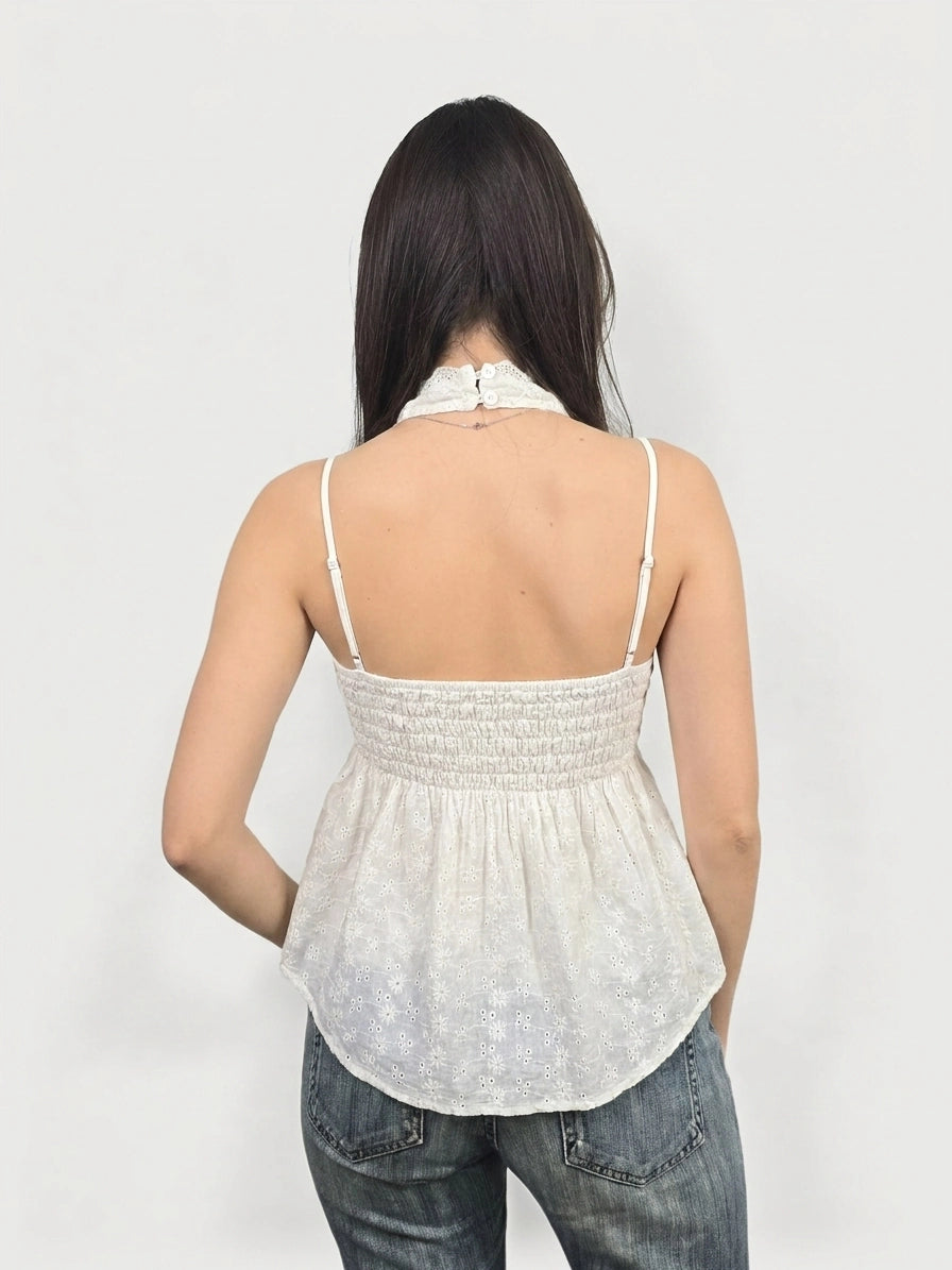 Back view of a white women’s top featuring lace trim and a smocked waist.