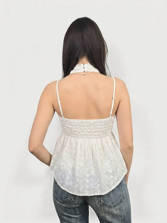 Back view of a white women’s top featuring lace trim and a smocked waist.