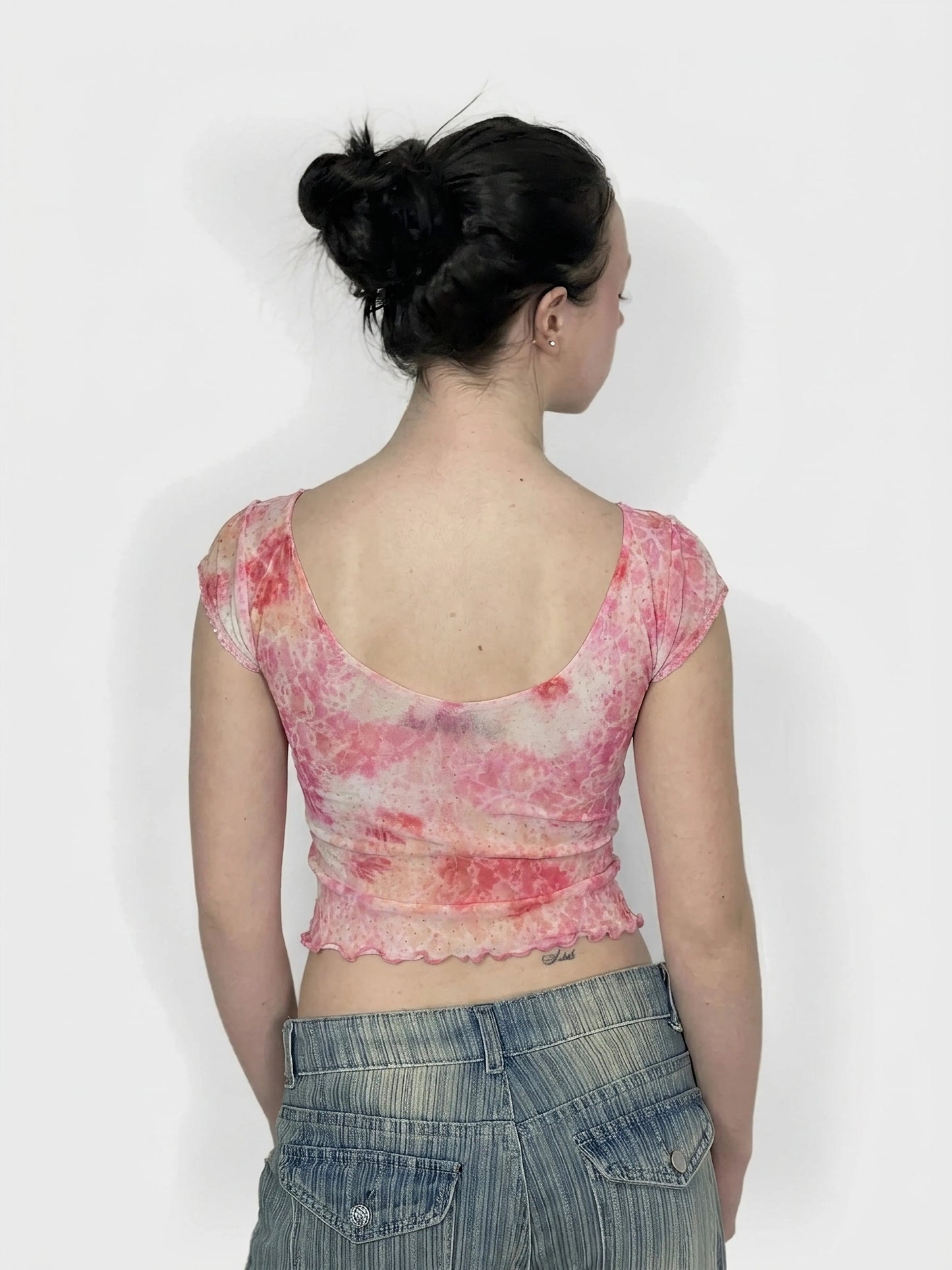 Back view of a pink tie-dye cropped top with scalloped trim.