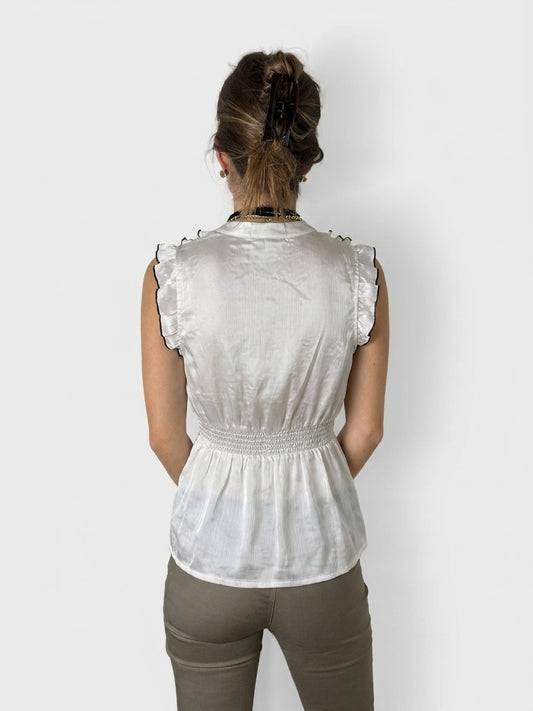 Back view of a cream upper body top with ruffled trim.