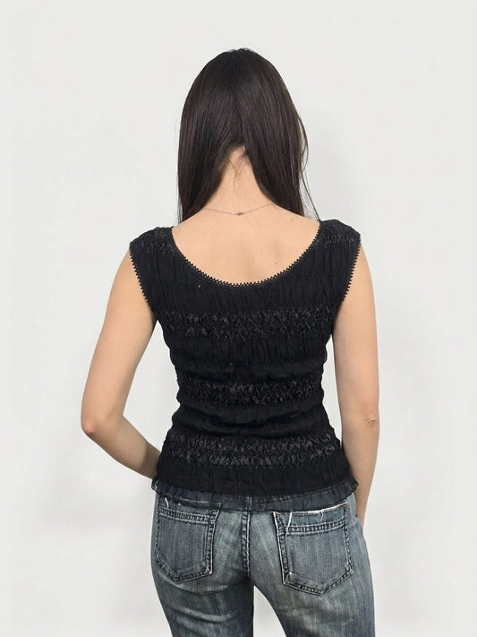 Black smocked top with lace trim, back view of garment worn by model.
