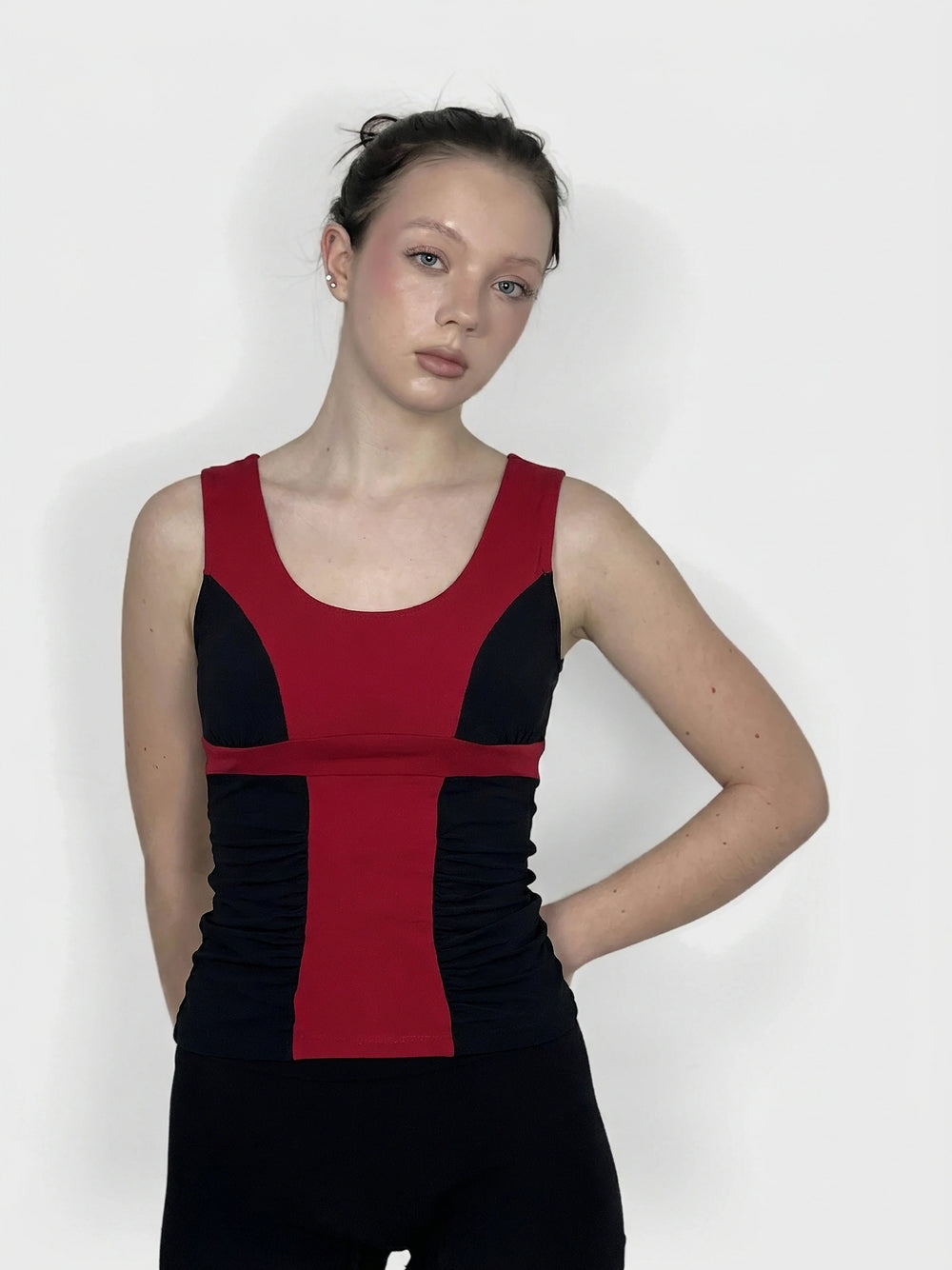 Front view of a sleeveless top in red and black with ruching detail.