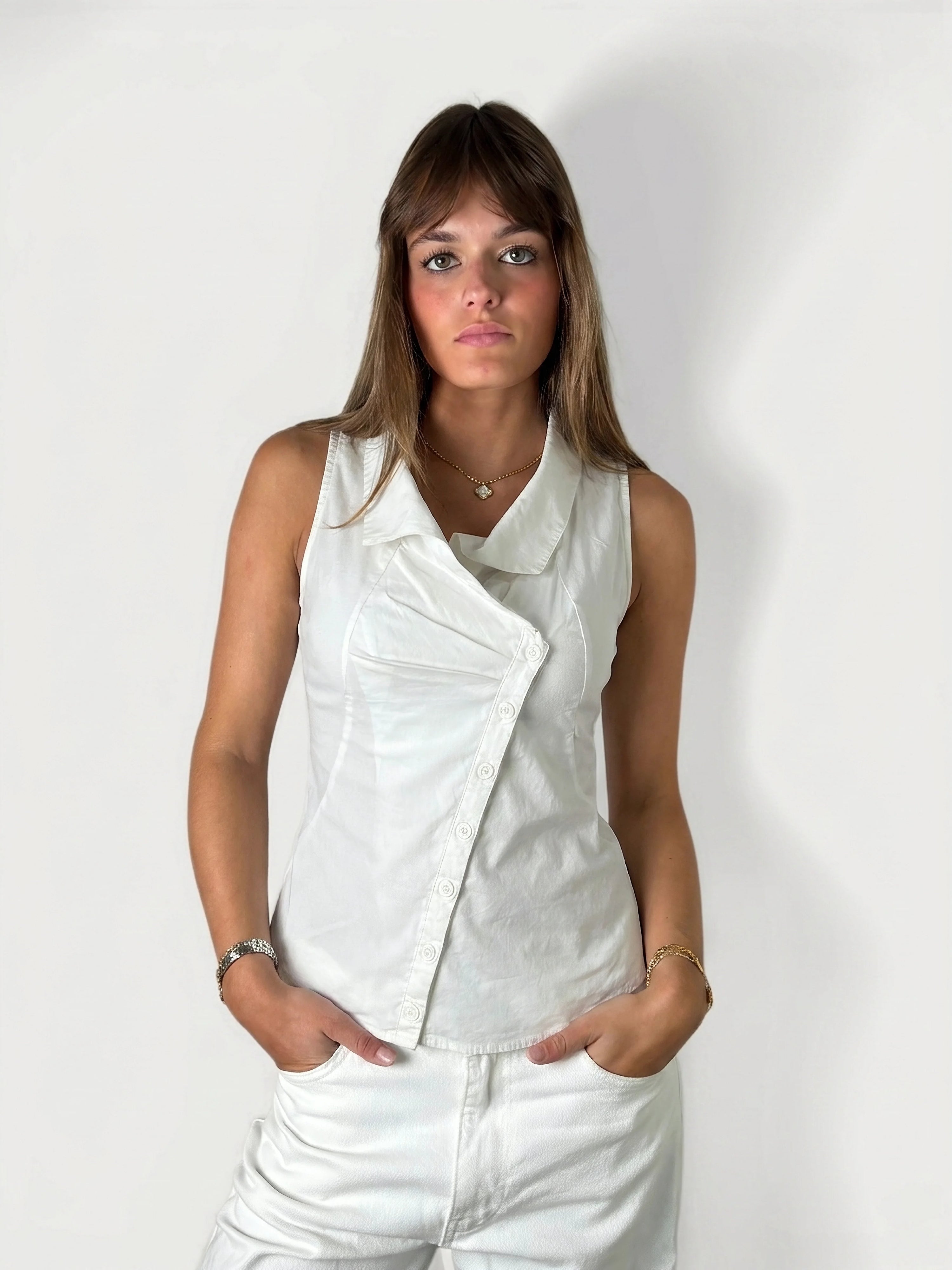 Front view of a sleeveless white top with a button detail.