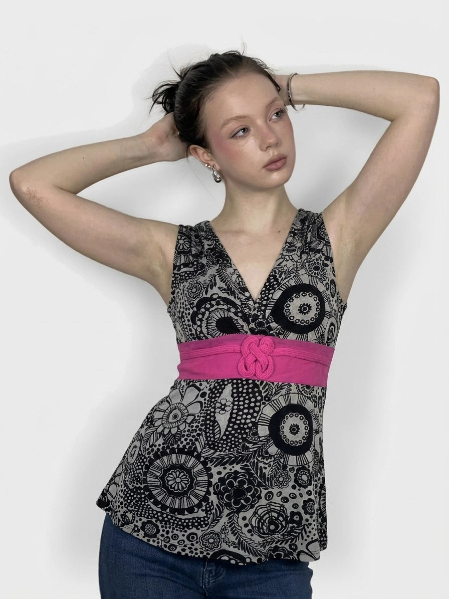 Front view of a women's black and white patterned top with a pink belt.
