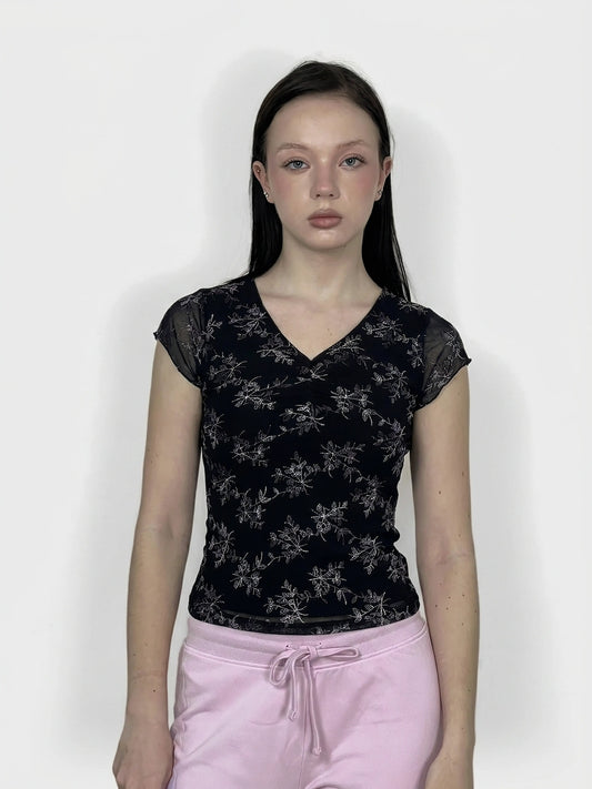 Women's upper body top in black with floral print, front view.