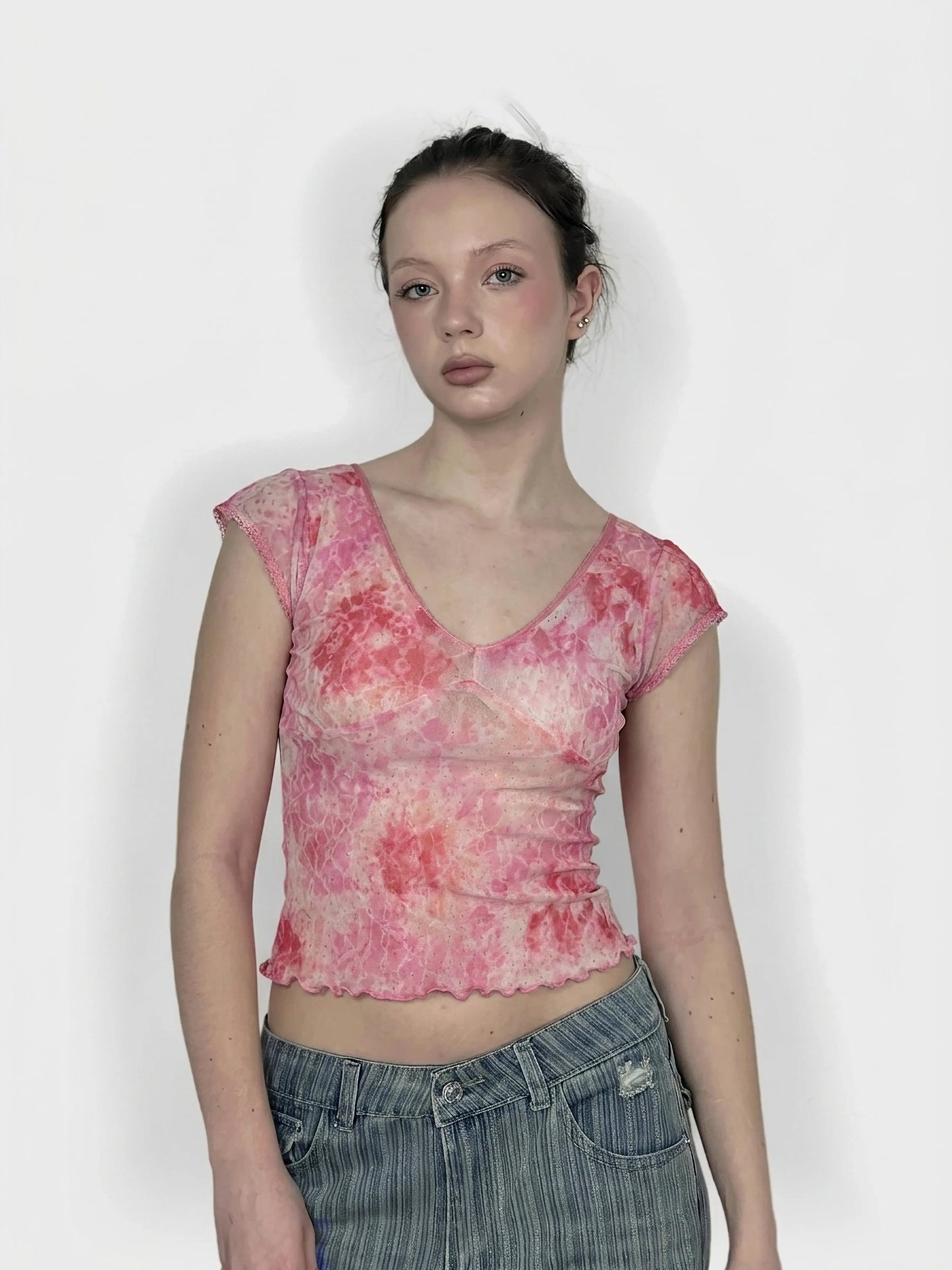 Front view of a pink, tie-dye short-sleeve top with a scalloped hem.