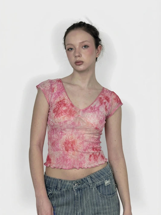 Front view of a pink, tie-dye short-sleeve top with a scalloped hem.