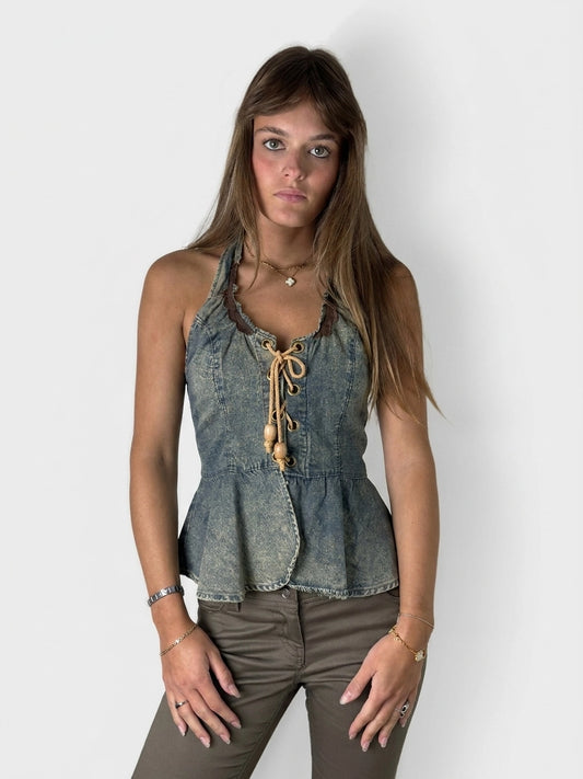 Front view of a denim peplum top with laces and a ruffled neckline.