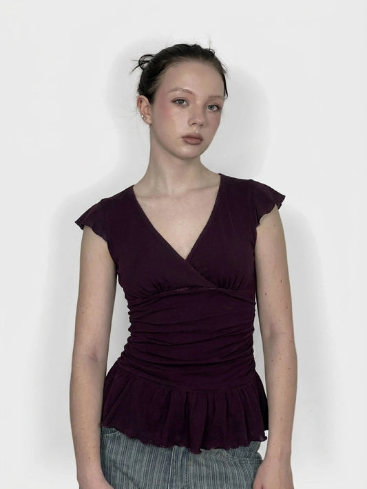 Front view of a purple peplum top with short sleeves and a v-neck.